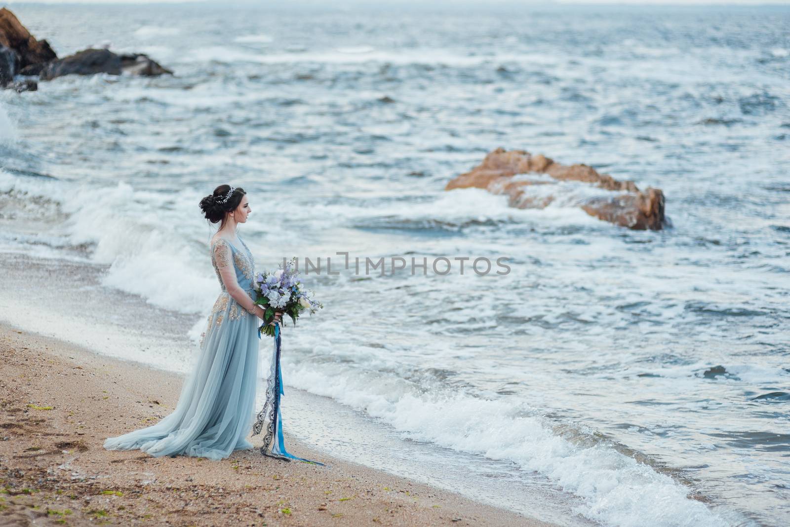 bride with a bouquet of flowers on the beach near the water