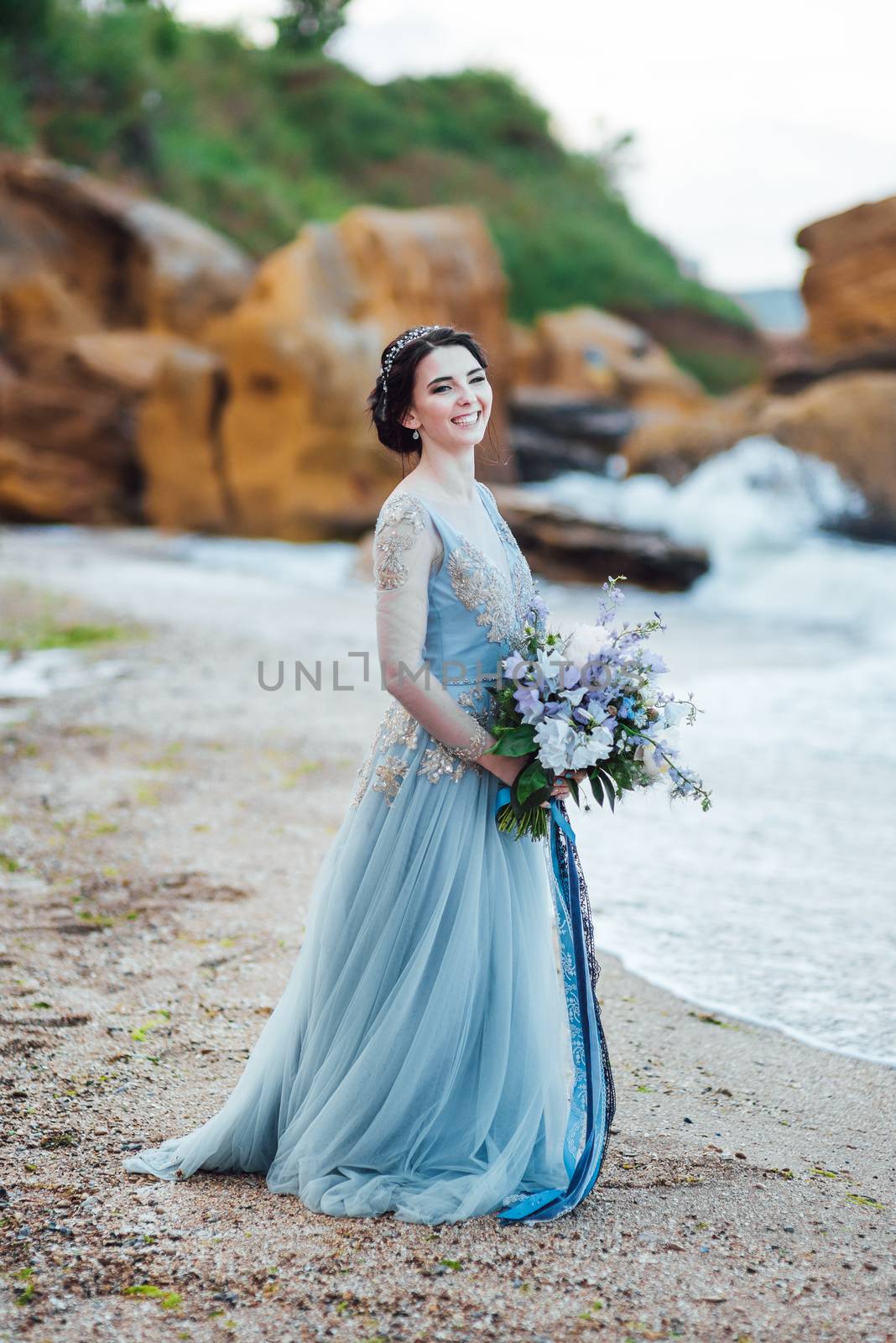 bride with a bouquet of flowers on the beach near the water