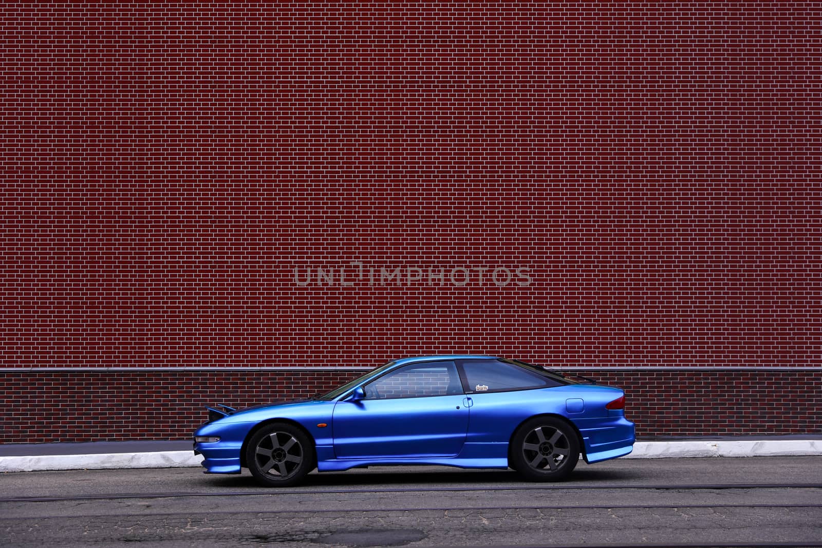 Blue Ford Probe behind a red brick wall