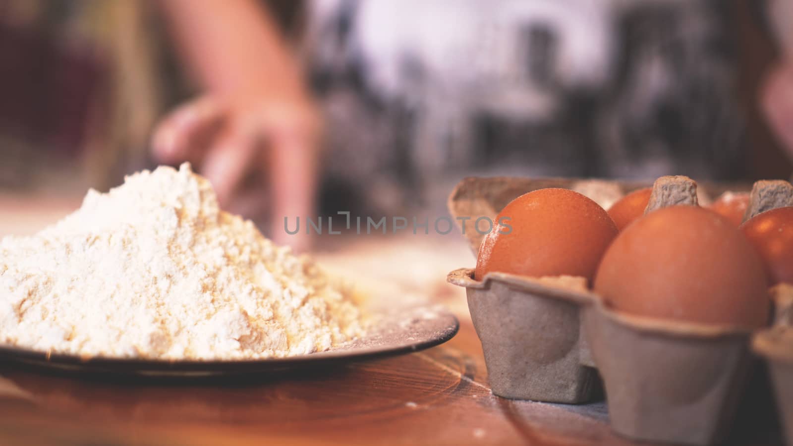 Ingredients for baking homemade bread. Eggs, flour. Wooden background, side view. Soft focus and light