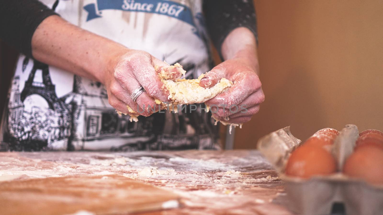 Cooking and home concept - close up of female hands kneading dough at home. Soft focus