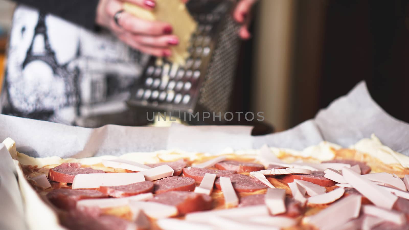 Closeup hand of chef baker making homemade pizza. Female hands rubbing cheese on pizza