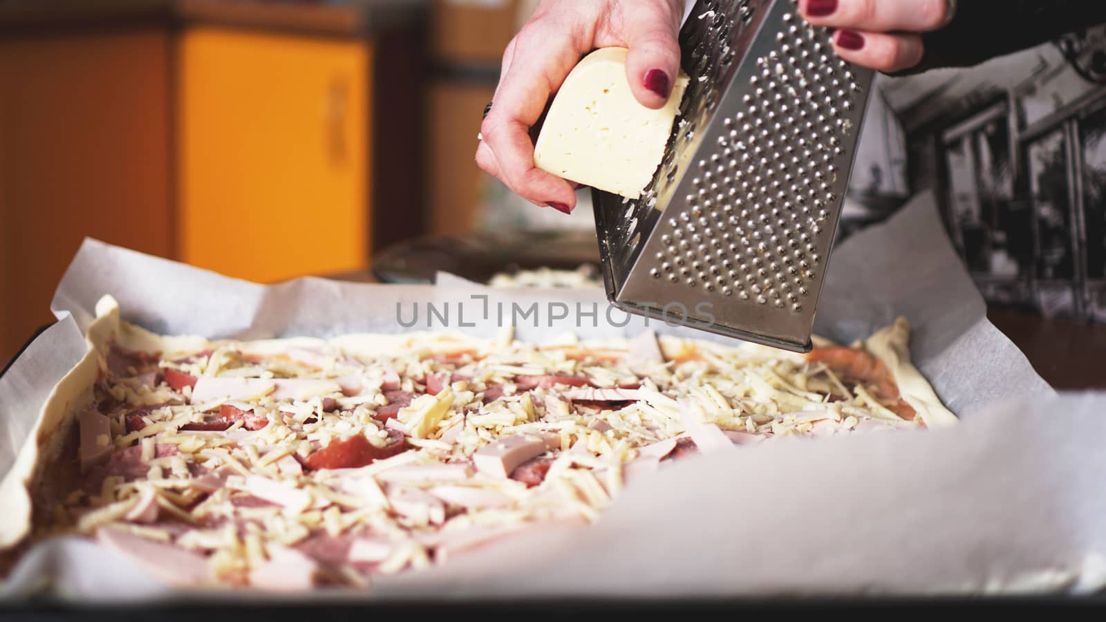 Closeup hand of chef baker making homemade pizza. Female hands rubbing cheese on pizza