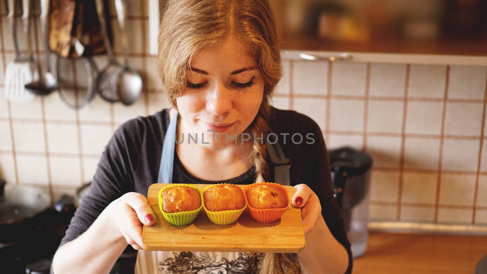 Woman smelling the taste of her homemade muffins while standing on a kitchen by natali_brill