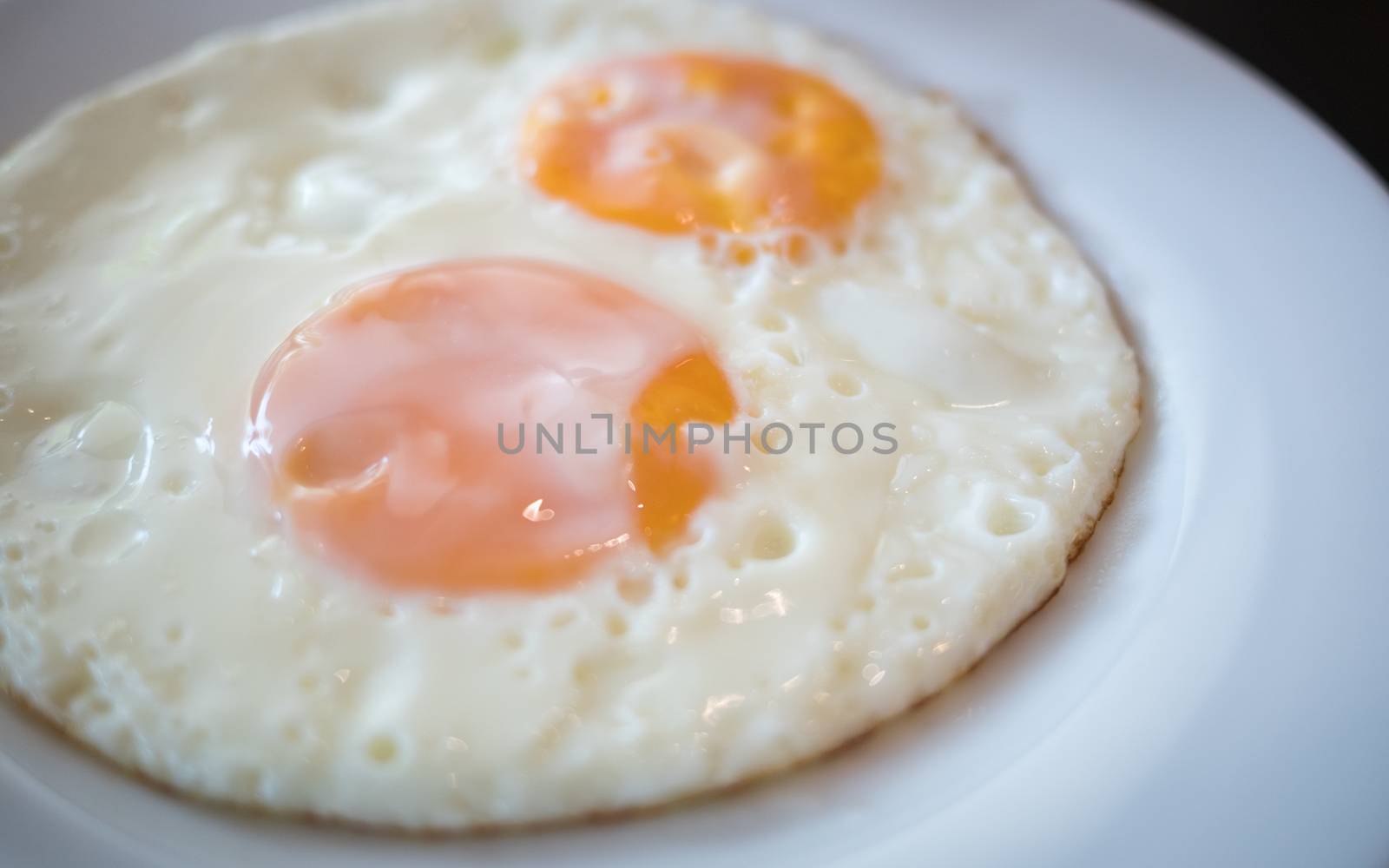 two fried egg on the white plate on breakfast table