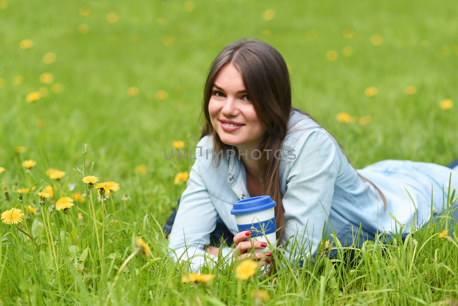 Woman laying on grass with coffee by ALotOfPeople