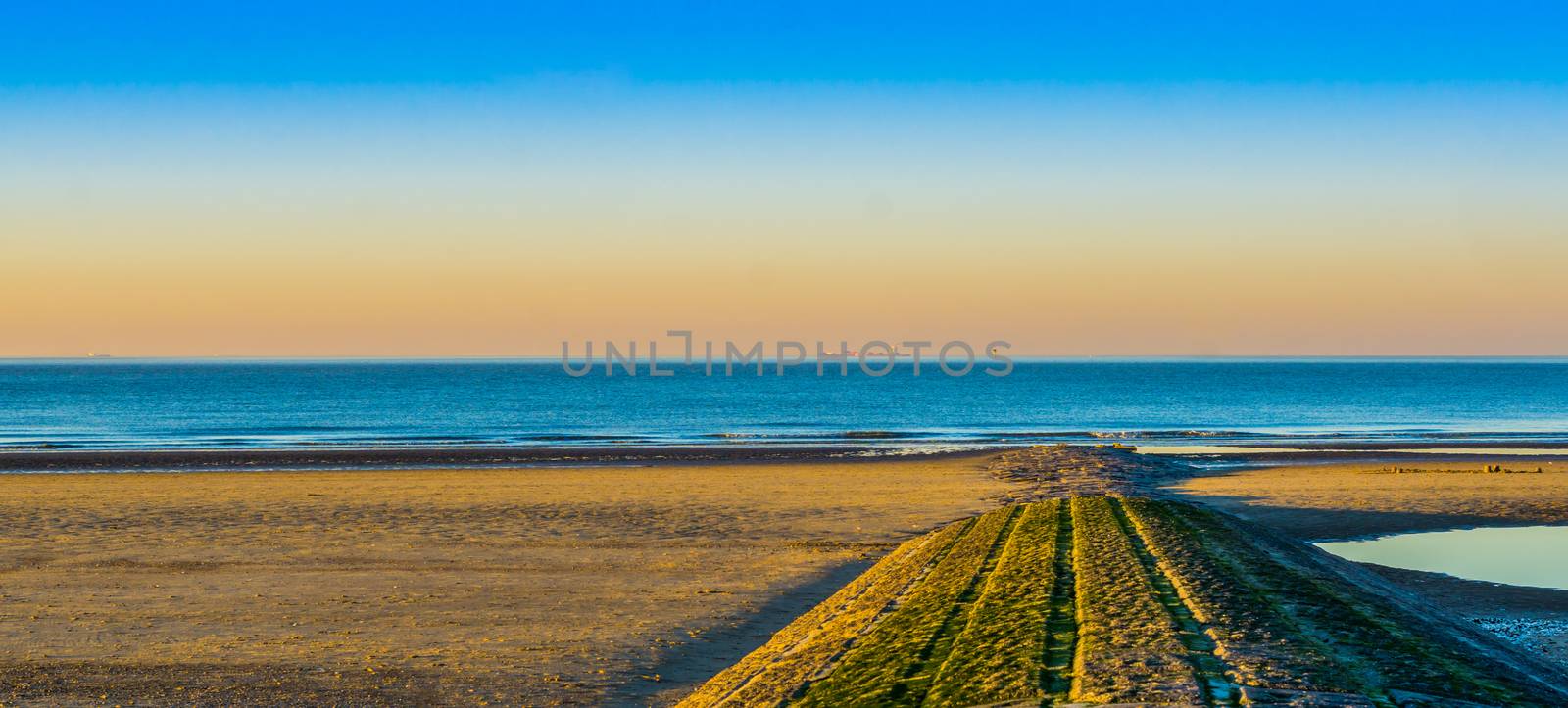 stone walking path of rocks leading to the sea, beautiful beach at sunset in Blankenberge, Belgium.