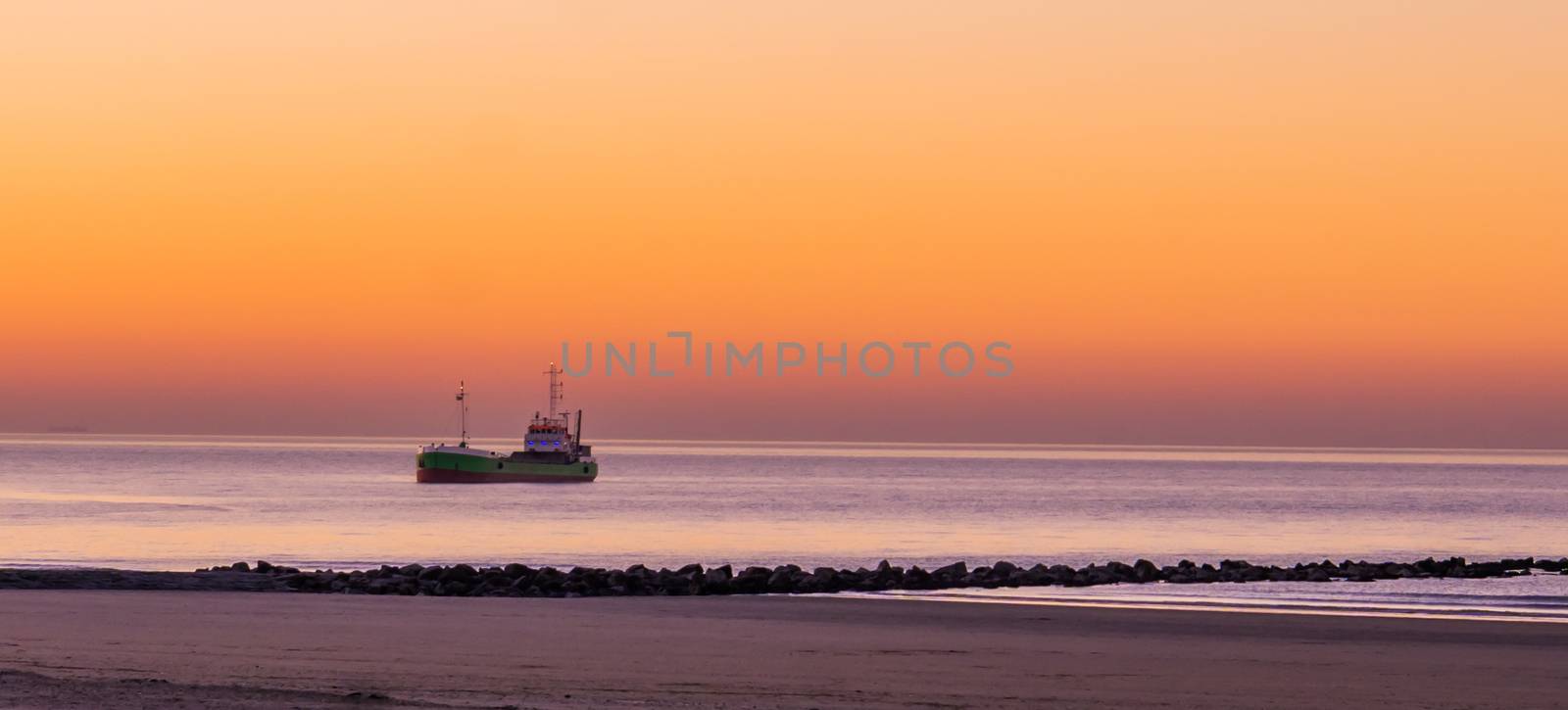 lighted ship sailing in the sea at sunset, the Belgian coast, nature and transport background by charlottebleijenberg