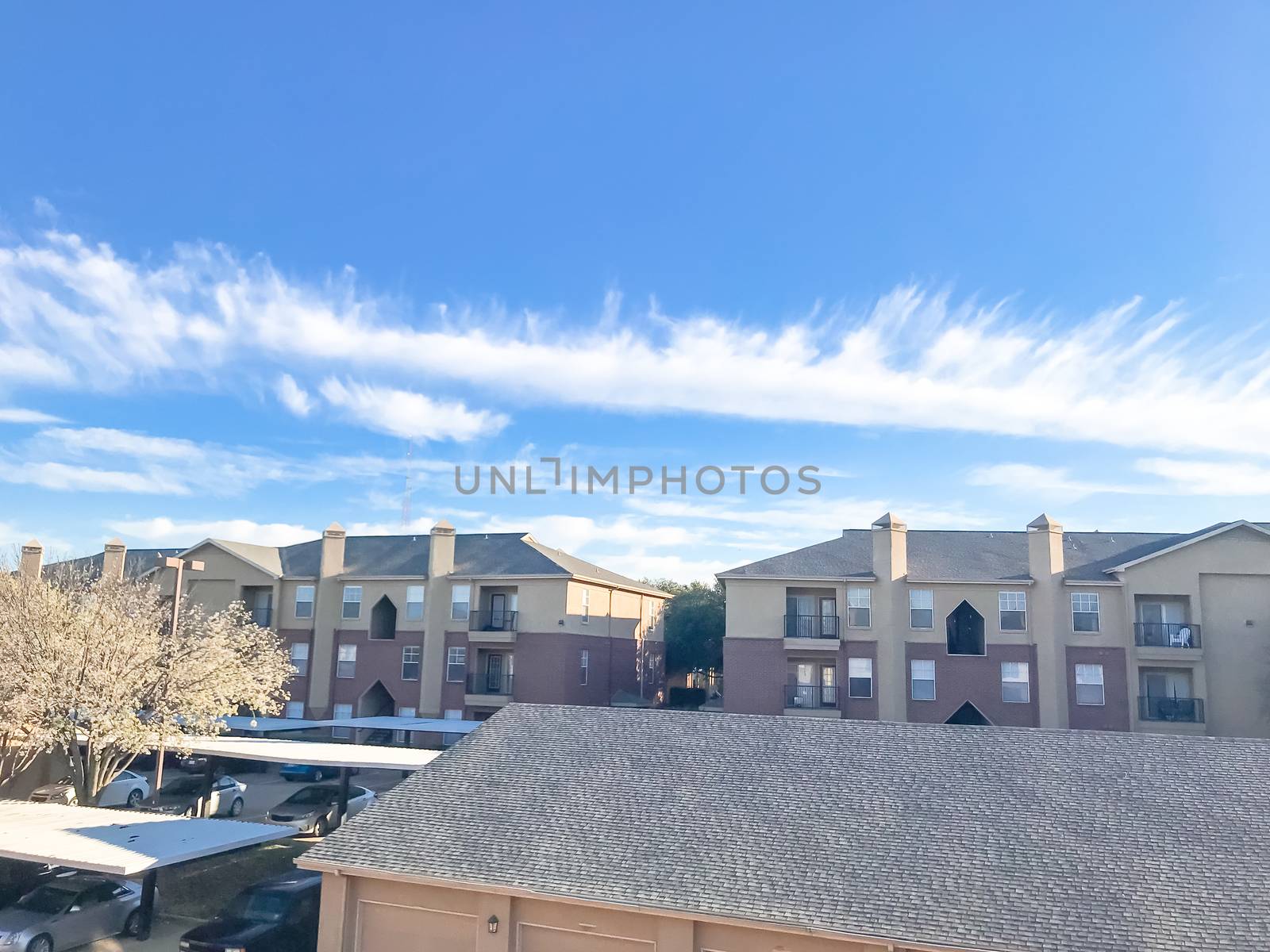 Typical aerial view of apartment complex with cover parking and detached garage in North Texas, America. Cloud sky at sunset in spring time with Bradford  pear flower blooming
