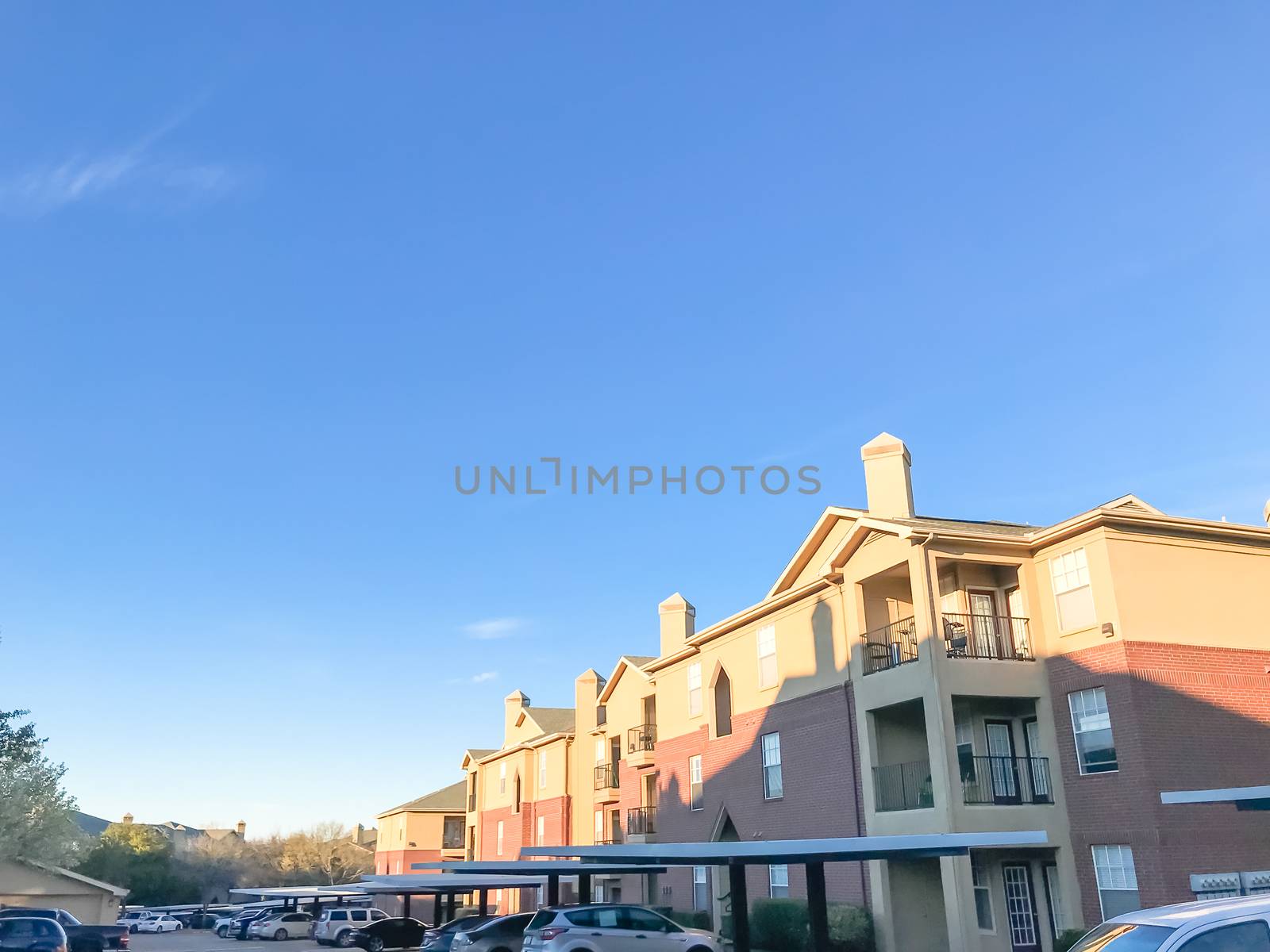 Typical apartment complex with cars at covered parking in Texas, by trongnguyen