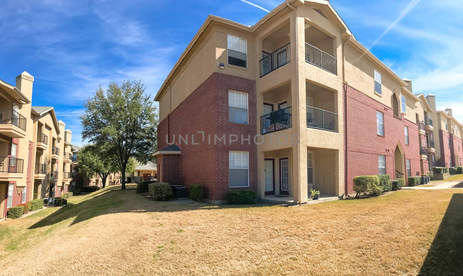 Panorama view modern apartment complex building with steep backyard in Lewisville, Texas, USA. Sunny spring day with cloud blue sky