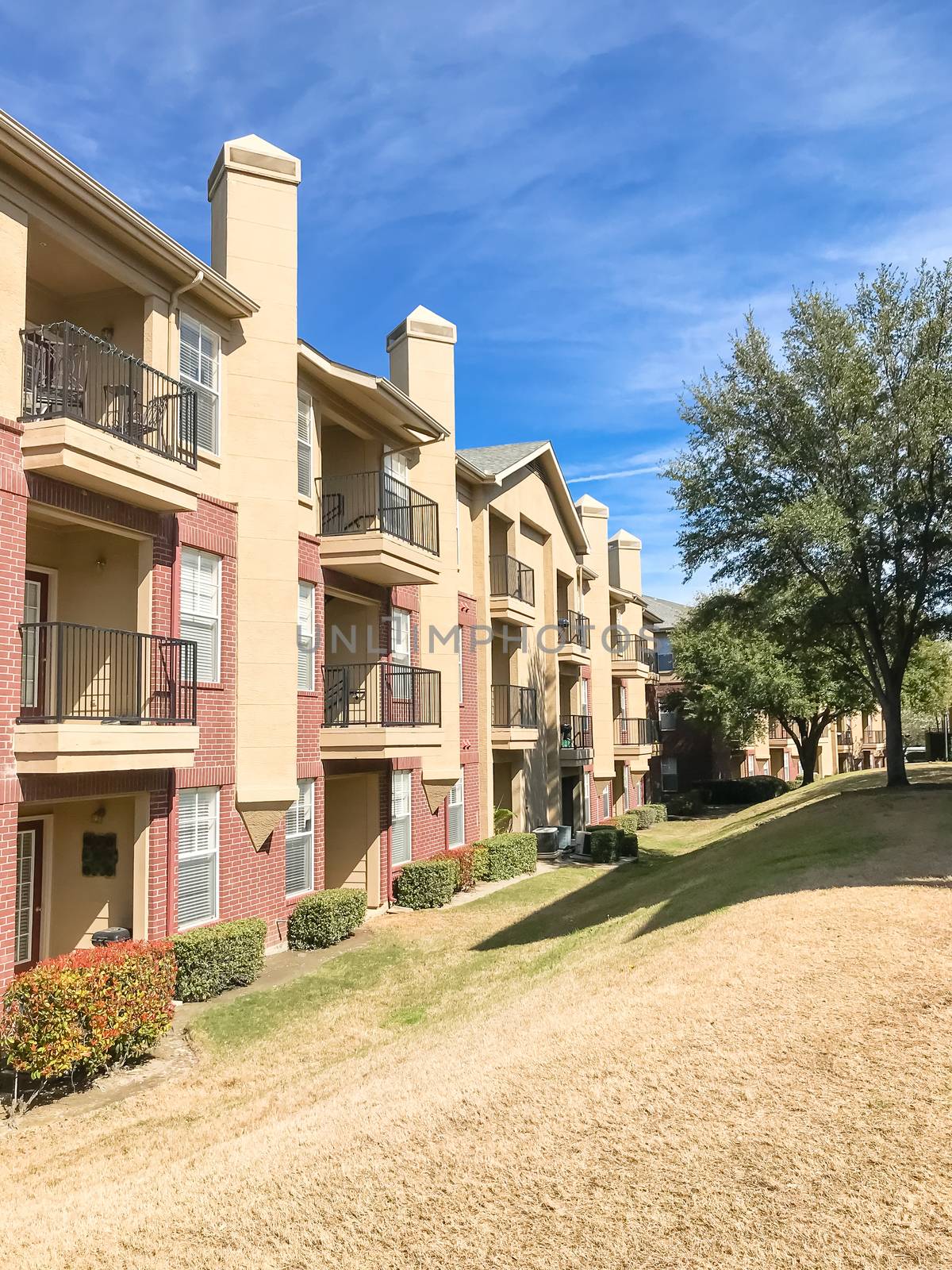 Typical apartment complex building with hillside backyard in Lewisville, Texas, USA. Sunny spring day with blue sky and white clouds over high chimney