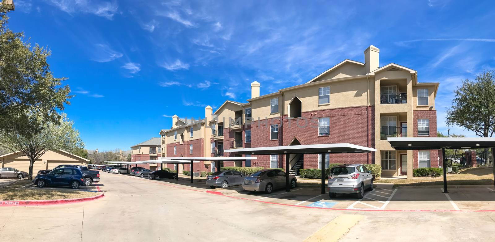 Panorama view modern apartment complex building with steep backyard in Lewisville, Texas, USA. Sunny spring day with cloud blue sky