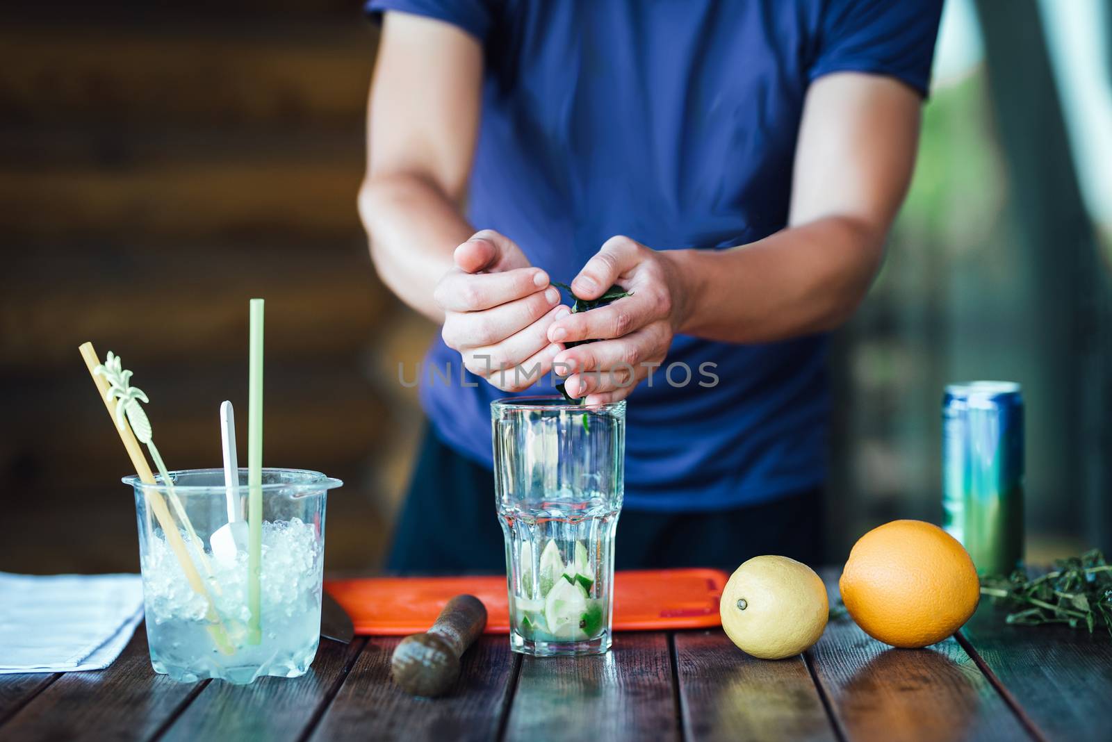 Barman prepares fruit alcohol cocktail based on lime, mint, oran by Andreua