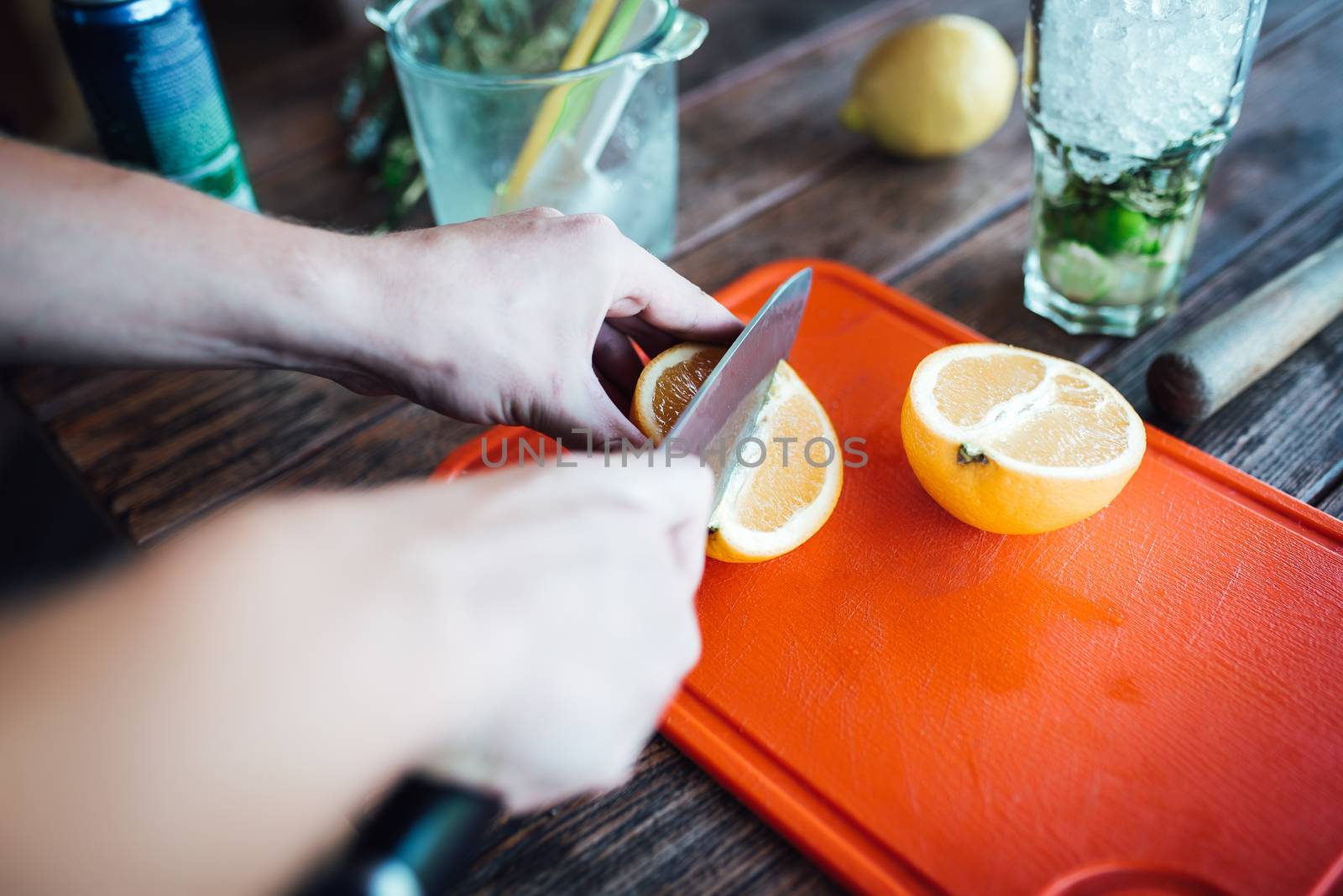 Barman prepares fruit alcohol cocktail based on lime, mint, oran by Andreua