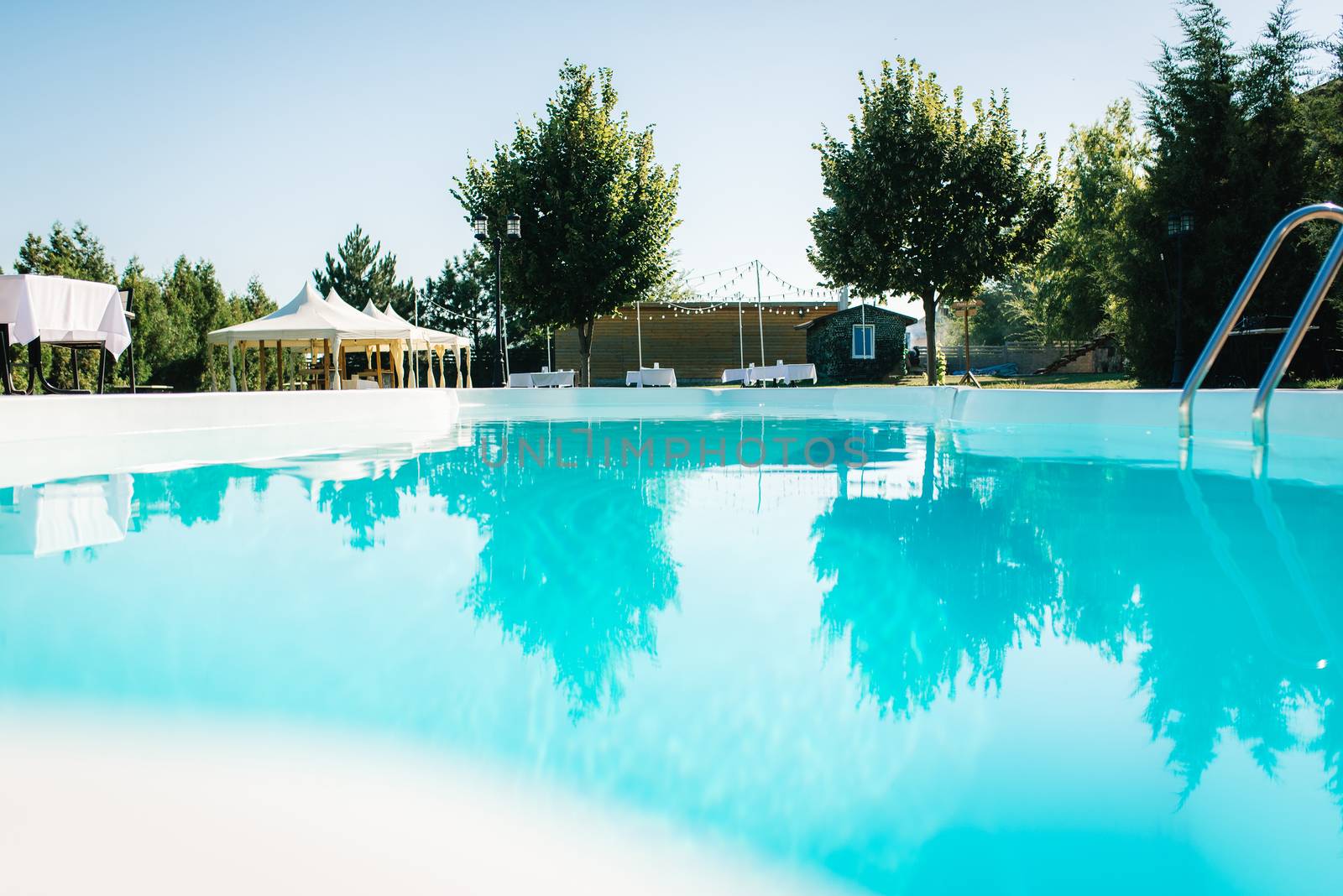 blue outdoor pool in the garden surrounded by coniferous trees