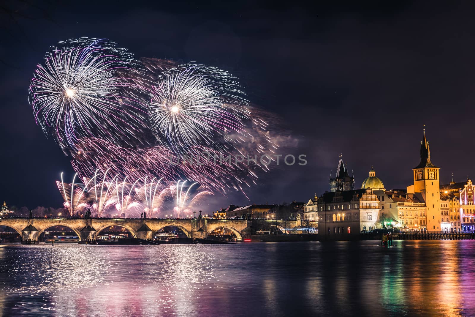 Beautiful fireworks above Charles bridge at night in Prague, historic center, Czech Republic, bautiful reflections in water.
