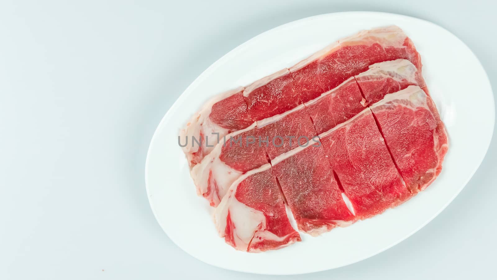 Top view of some raw beef on a plate over white background