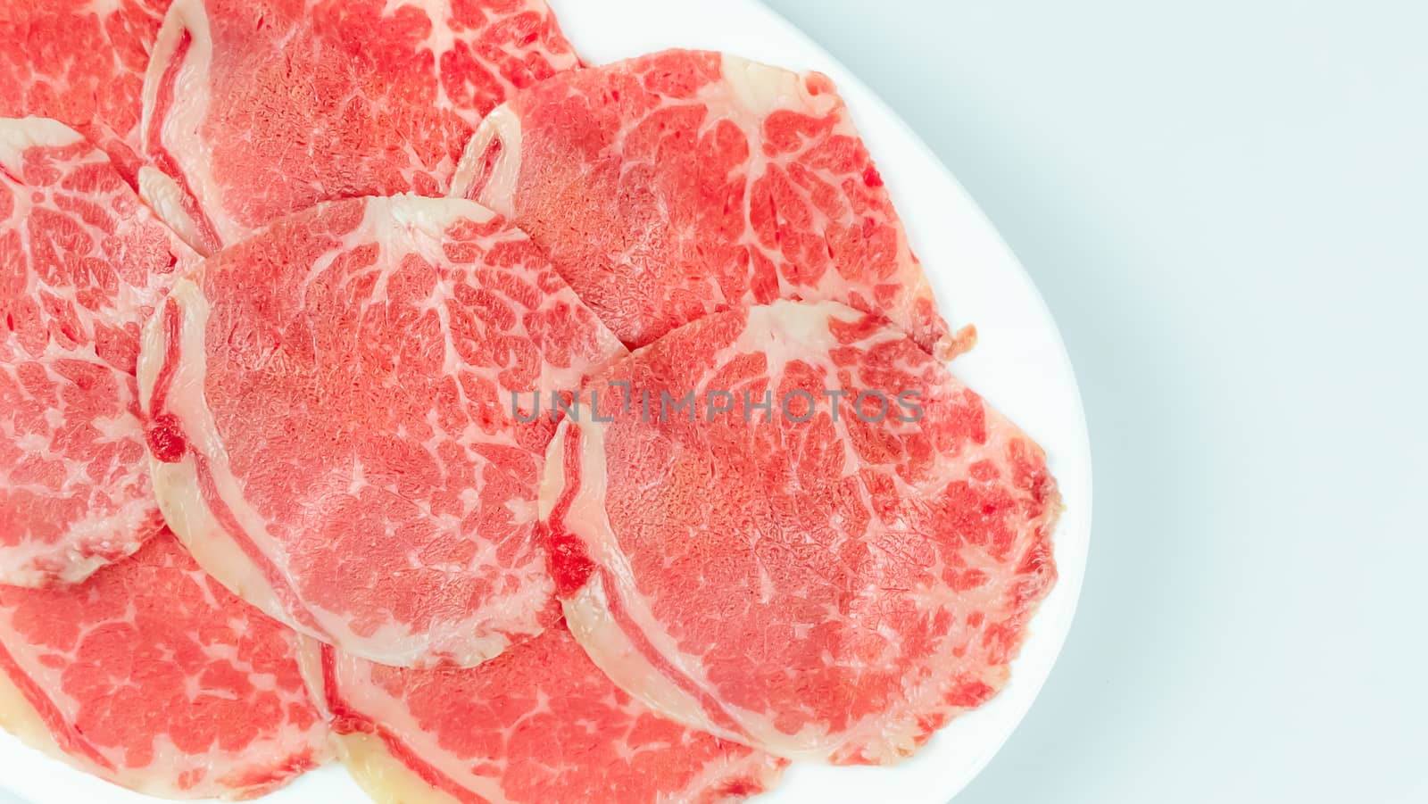 Top view of some raw beef on a plate over white background