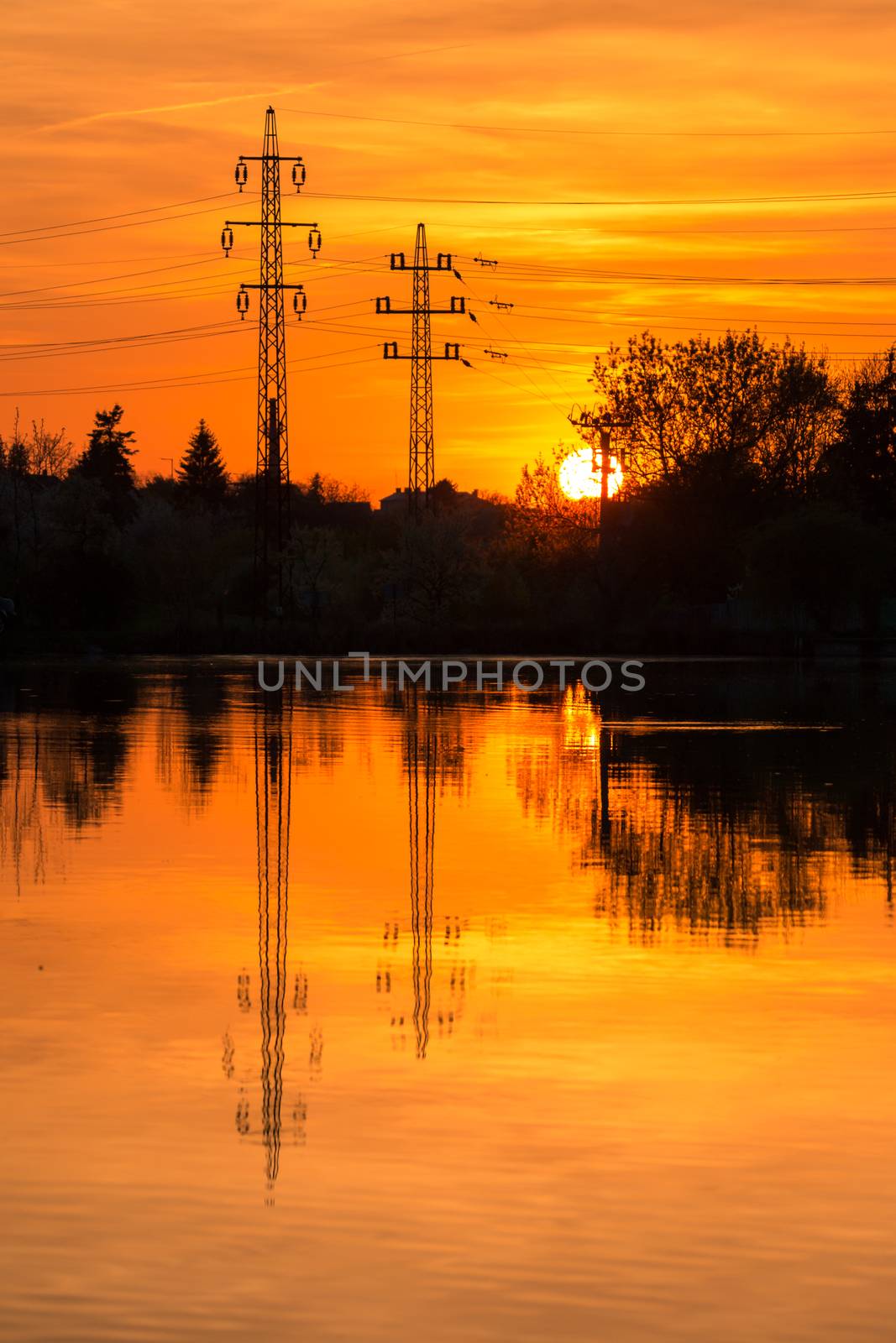 Electricity pylons on sunset background, reflection in a water. by petrsvoboda91