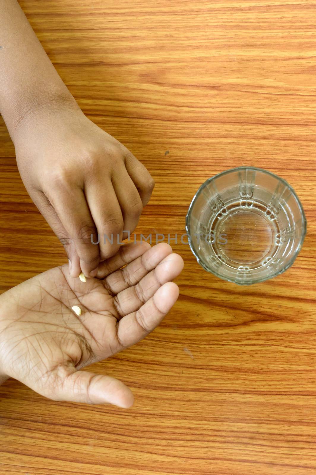 Self-treatment at home as per prescribed by doctor. A teenager boy pouring medicine into her hand. Medical, health care or people concept. High Angel view. Close up with copy space room for text. by sudiptabhowmick