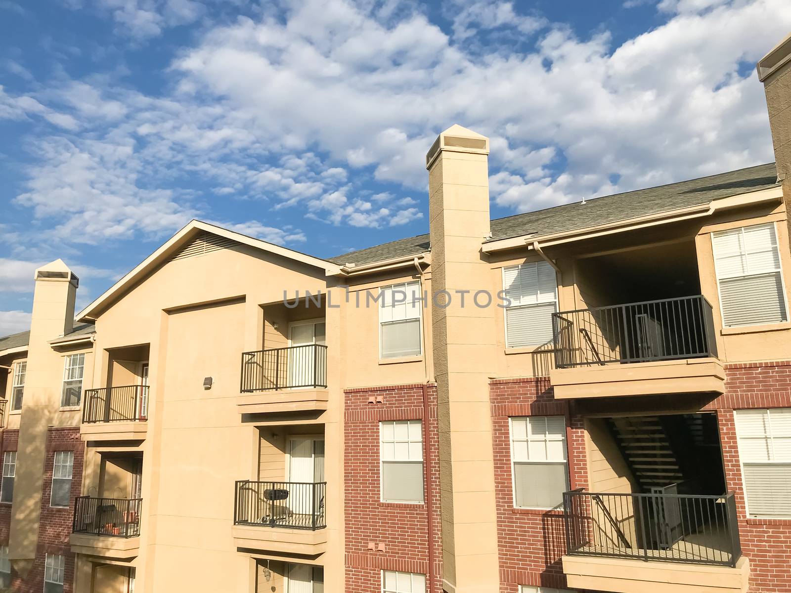 Apartment home building complex in suburban Dallas, Texas, USA. Low angle view of multi-stories rental real estate at sunset with cloud sky