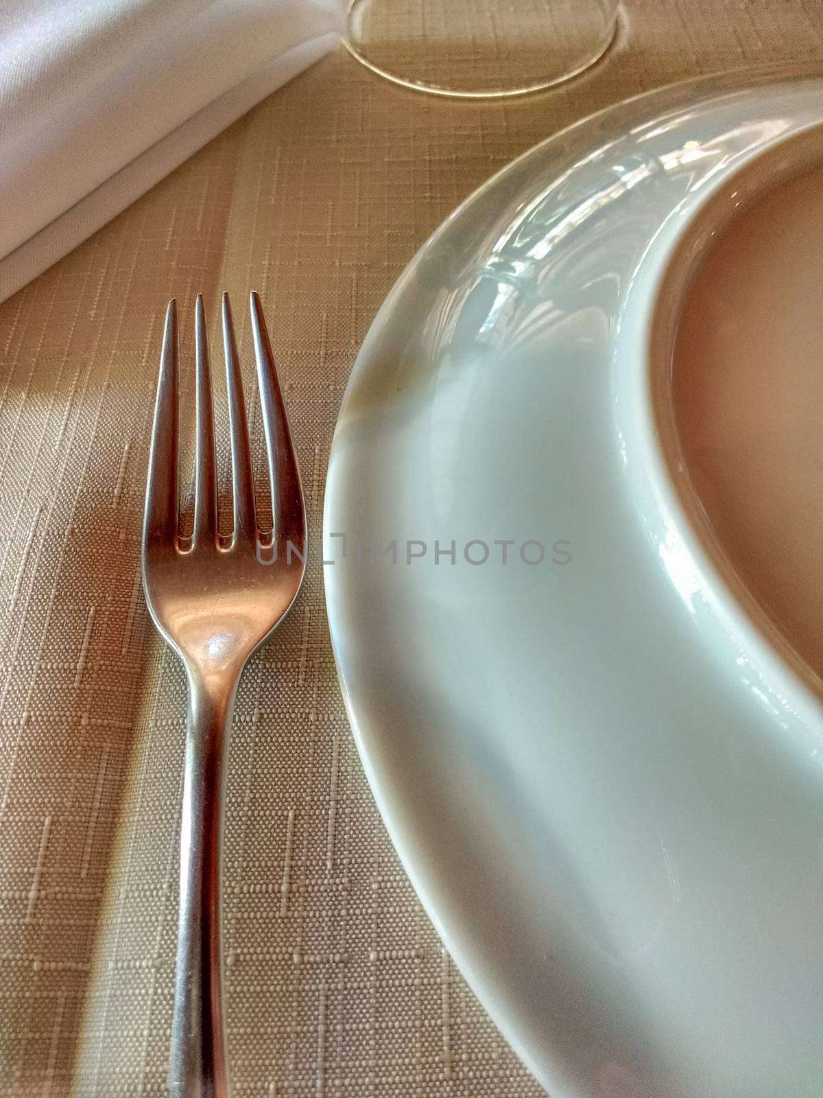 Fork, plate and napkin on tidy linen towel to start dinner, with soft light