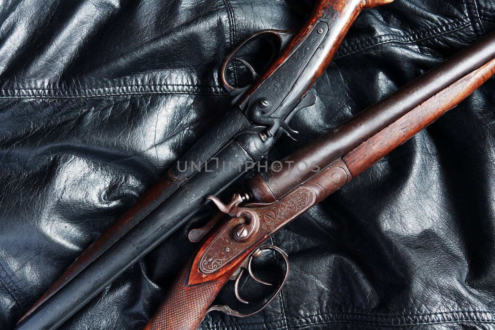 Pair of ancient hunting shotguns closeup on leather background