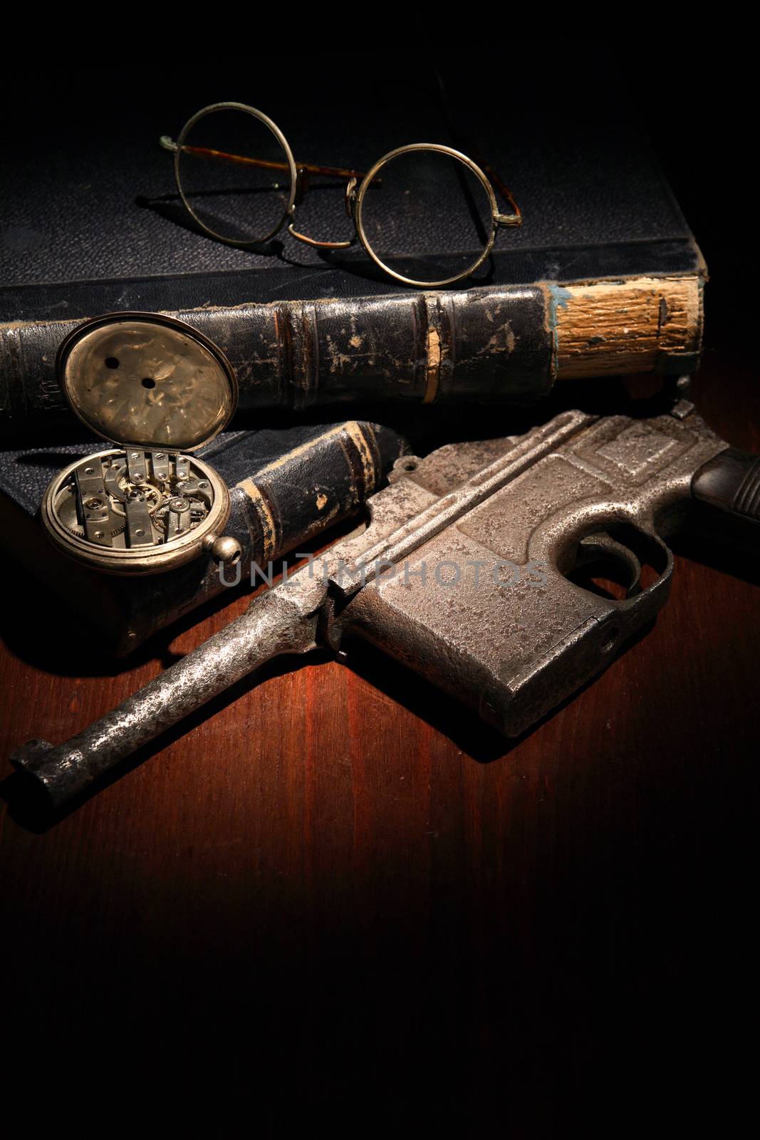 Vintage still life with handgun and spectacles near old books