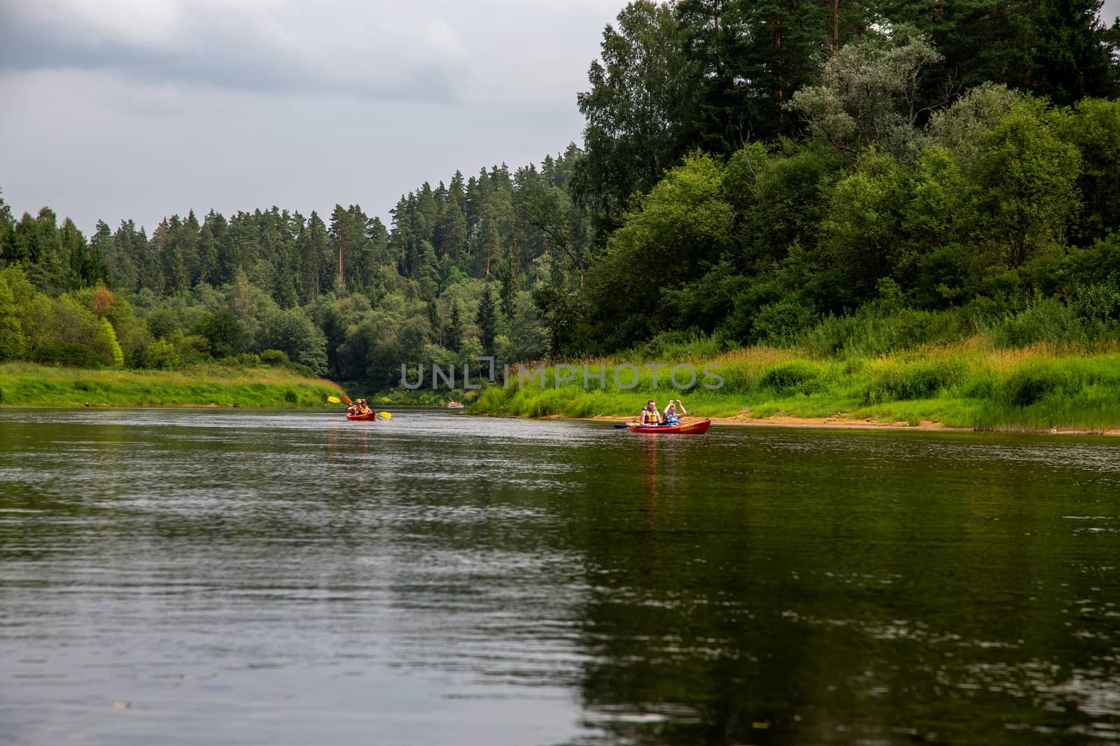 People boating on river Gauja in Latvia, peacefull nature scene. By boat through the river. Boat trip along the Gauja River in Latvia. The Gauja is the longest river in Latvia, which is located only in the territory of Latvia. Length - 452 km.

