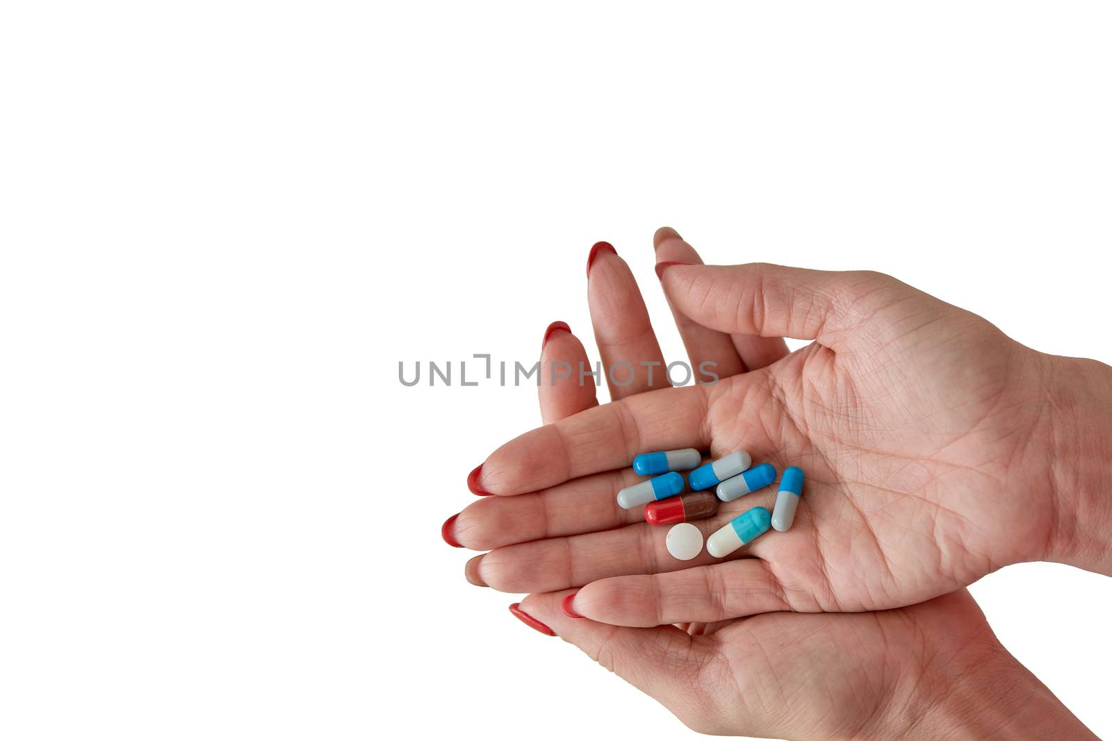 Colored assorted pharmaceutical medicine pills, tablets and capsules on female hand isoleted on white background. Close-up.