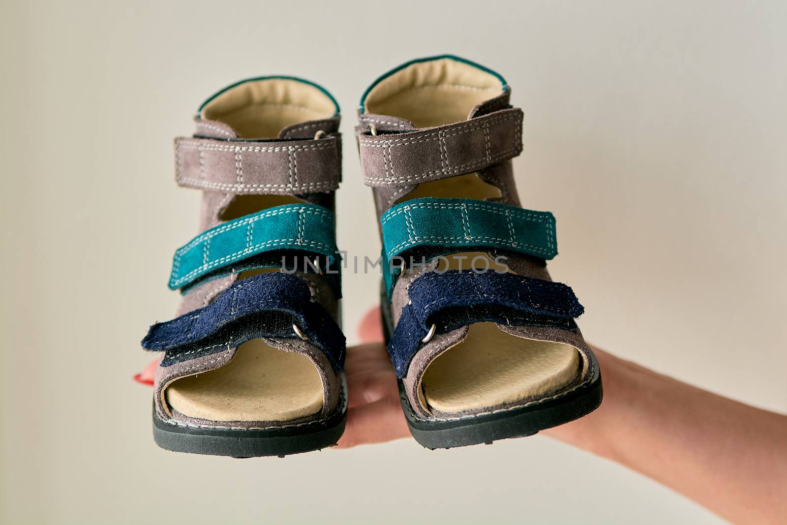 Female is holding close-up a special children's orthopedic shoe sandals made of genuine leather. by nixrenas