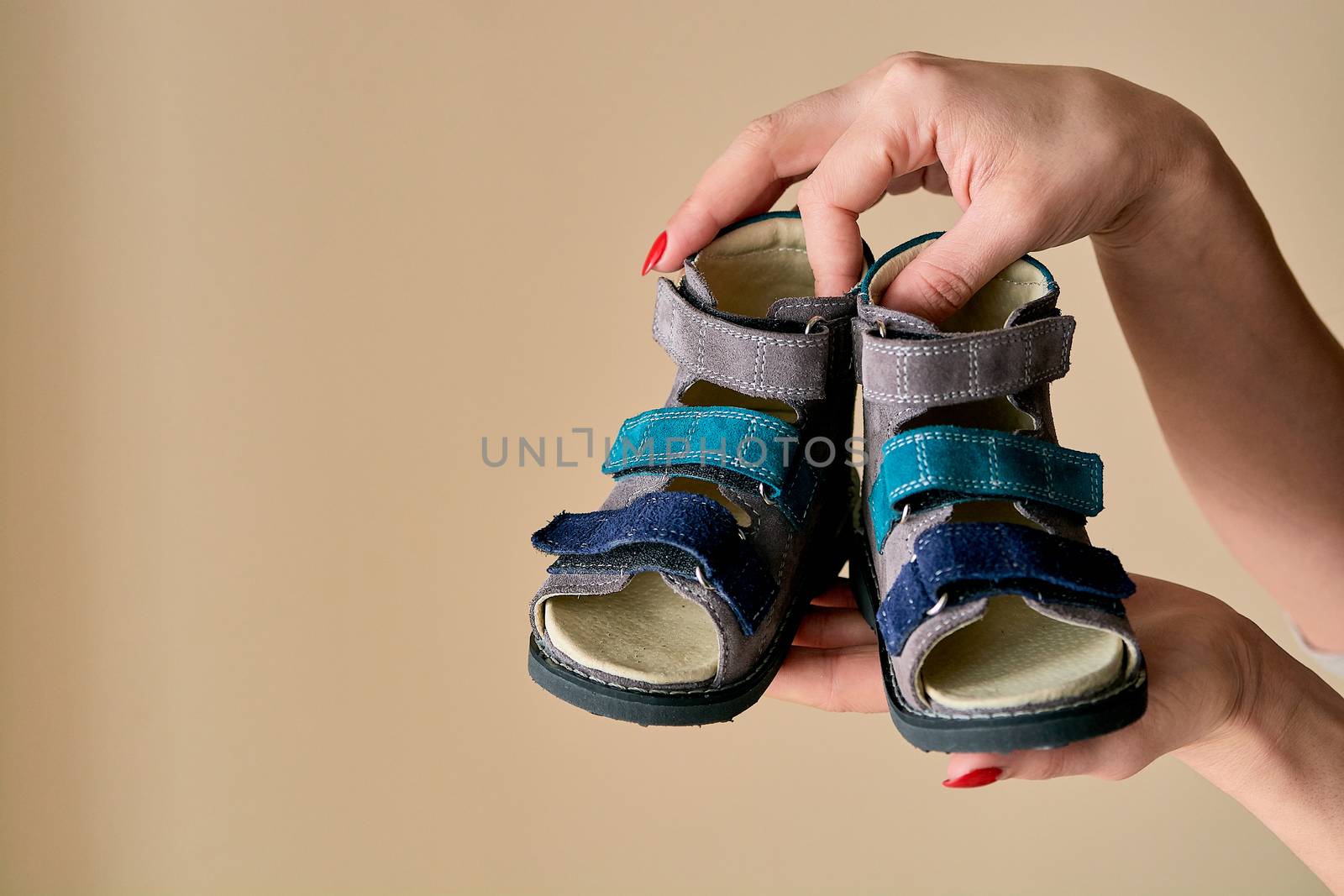 Female is holding close-up a special children's orthopedic shoe sandals made of genuine leather. by nixrenas