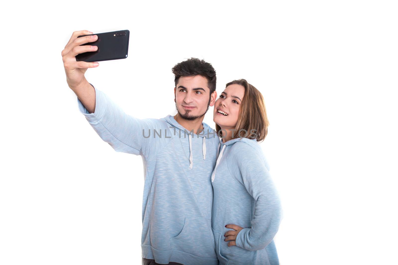 Young loving couple standing isolated on white and making selfie using mobile phone