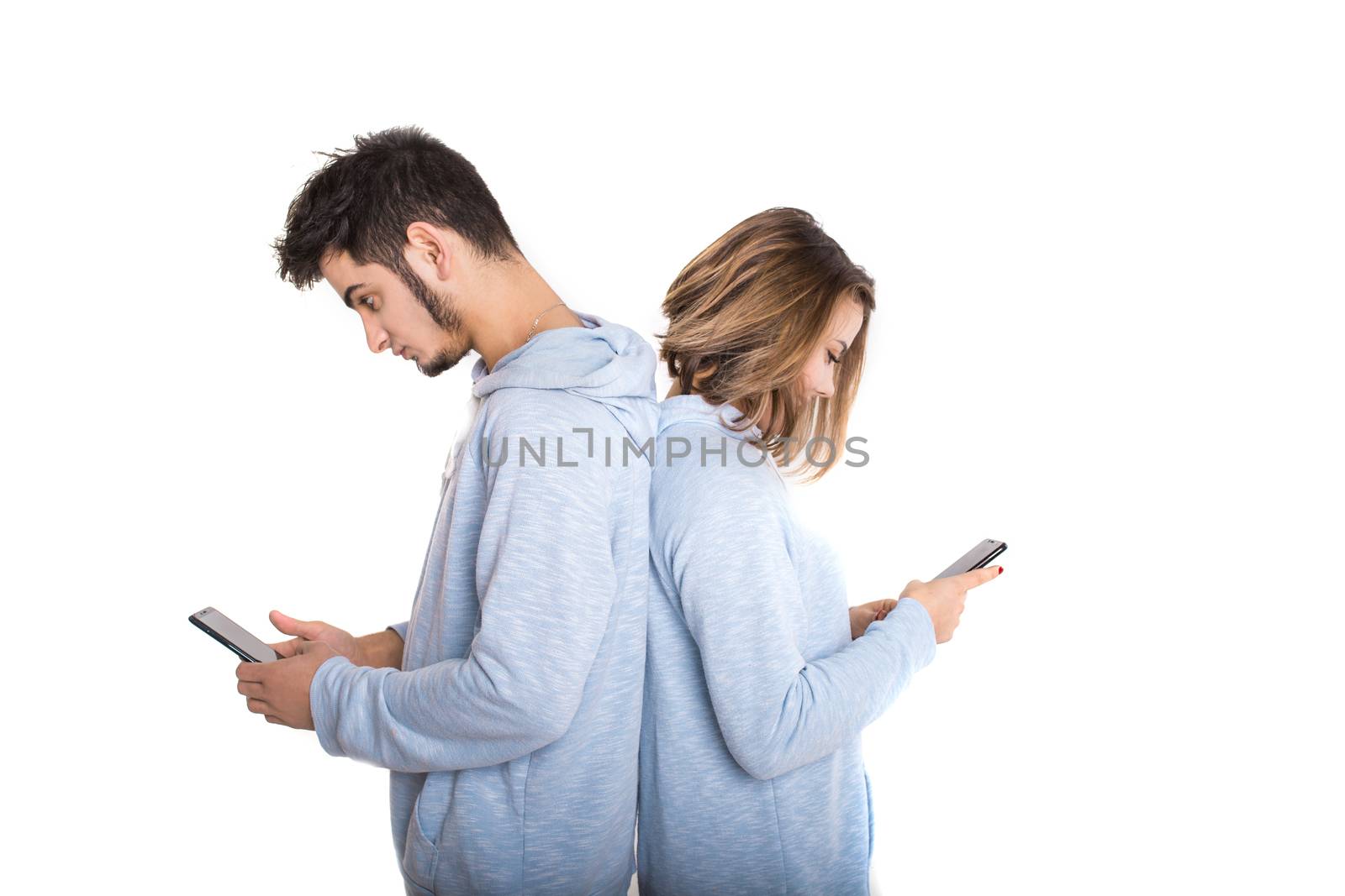 Unhappy couple backwards with their mobile phones isolated on white background