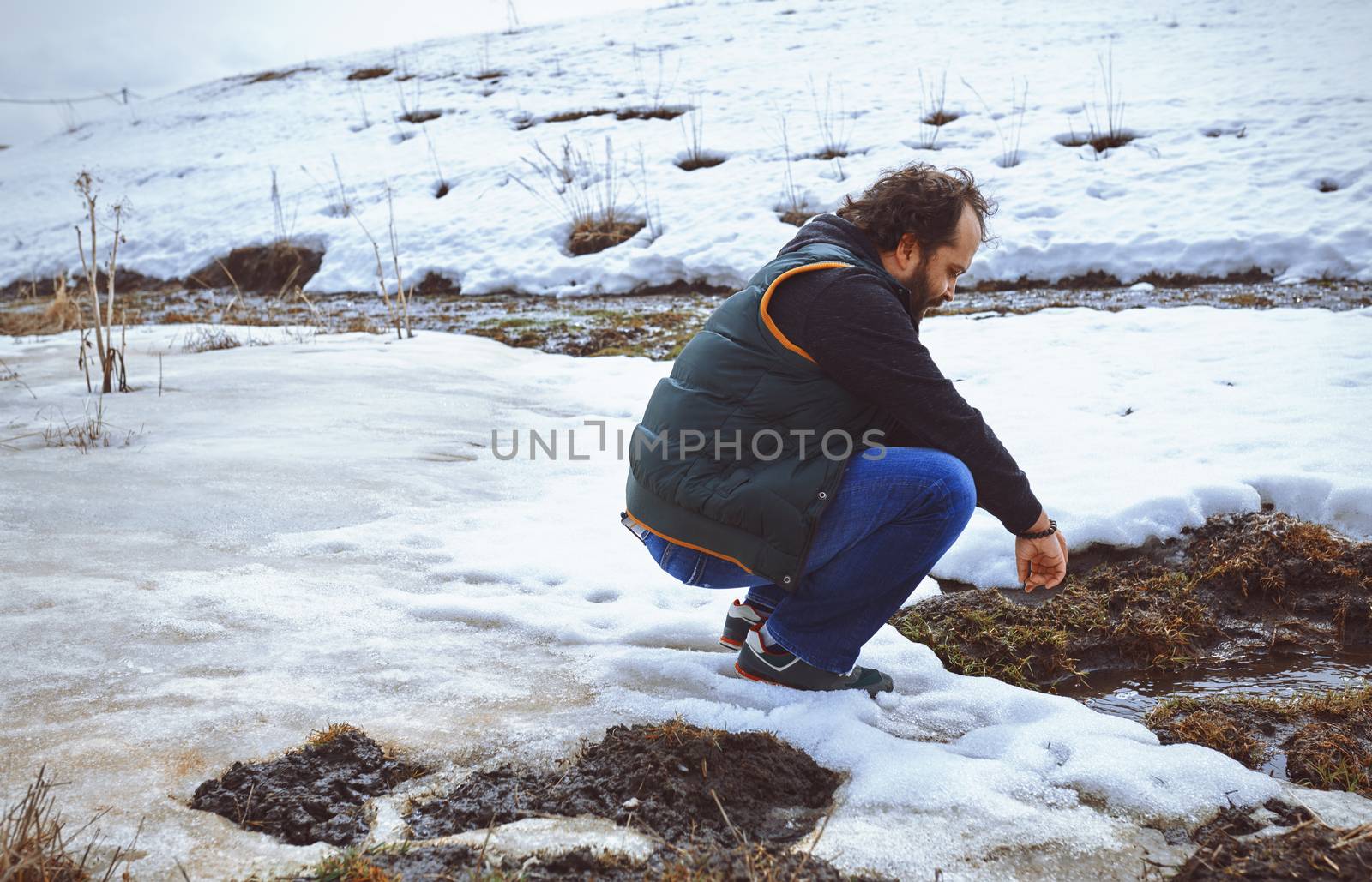 Traveller squatting at the snowy marsh