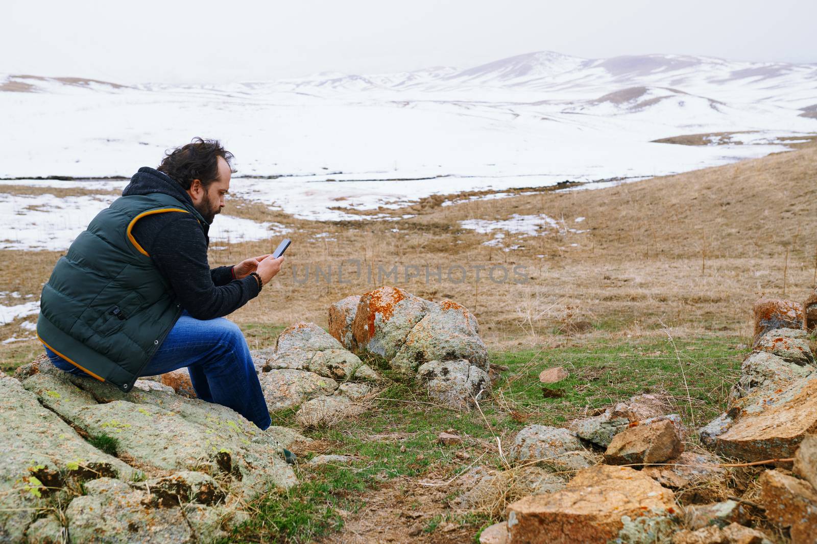 Man in snow landscape using GPS on his smartphone