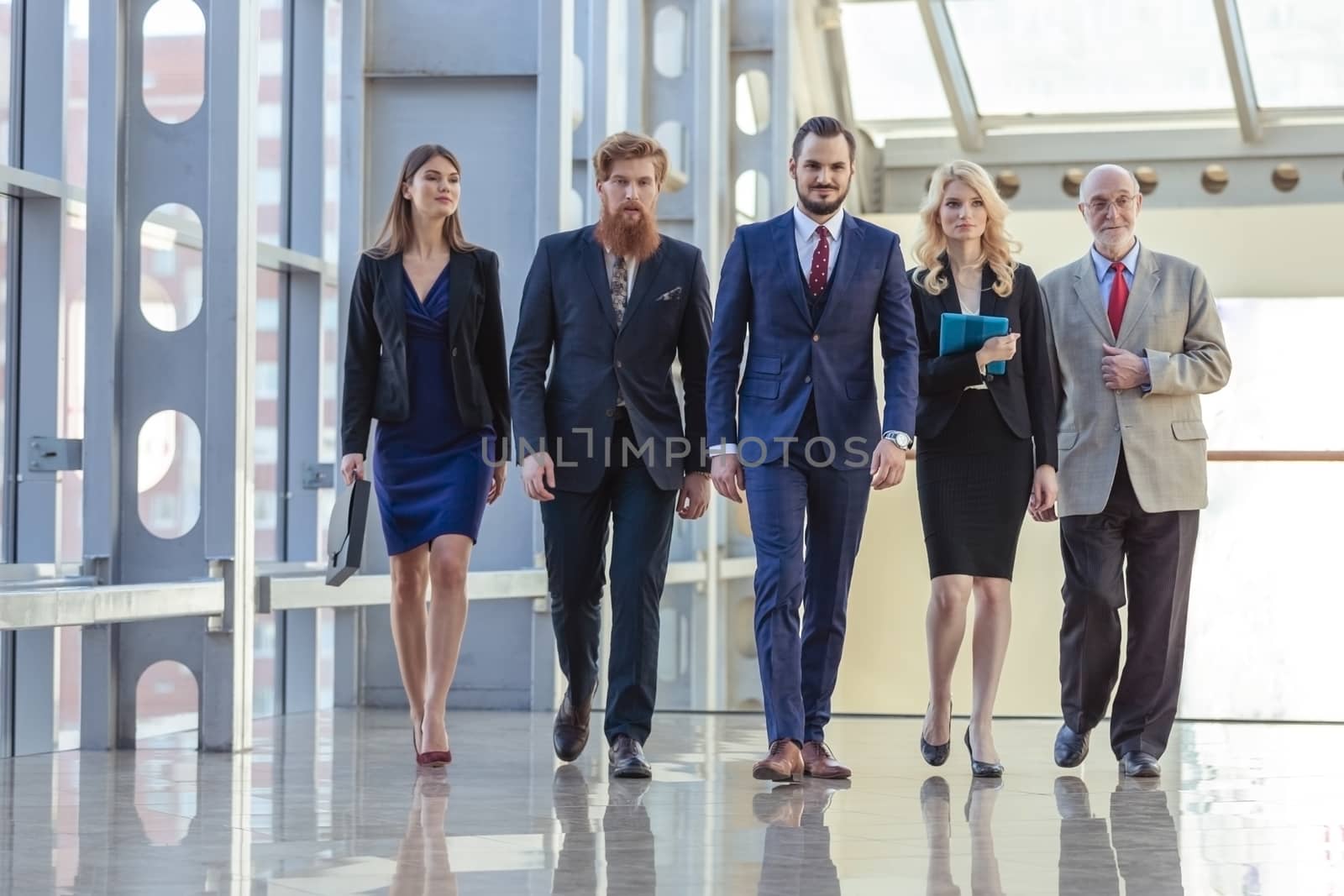 Full length of group of happy young business people walking the corridor in office together