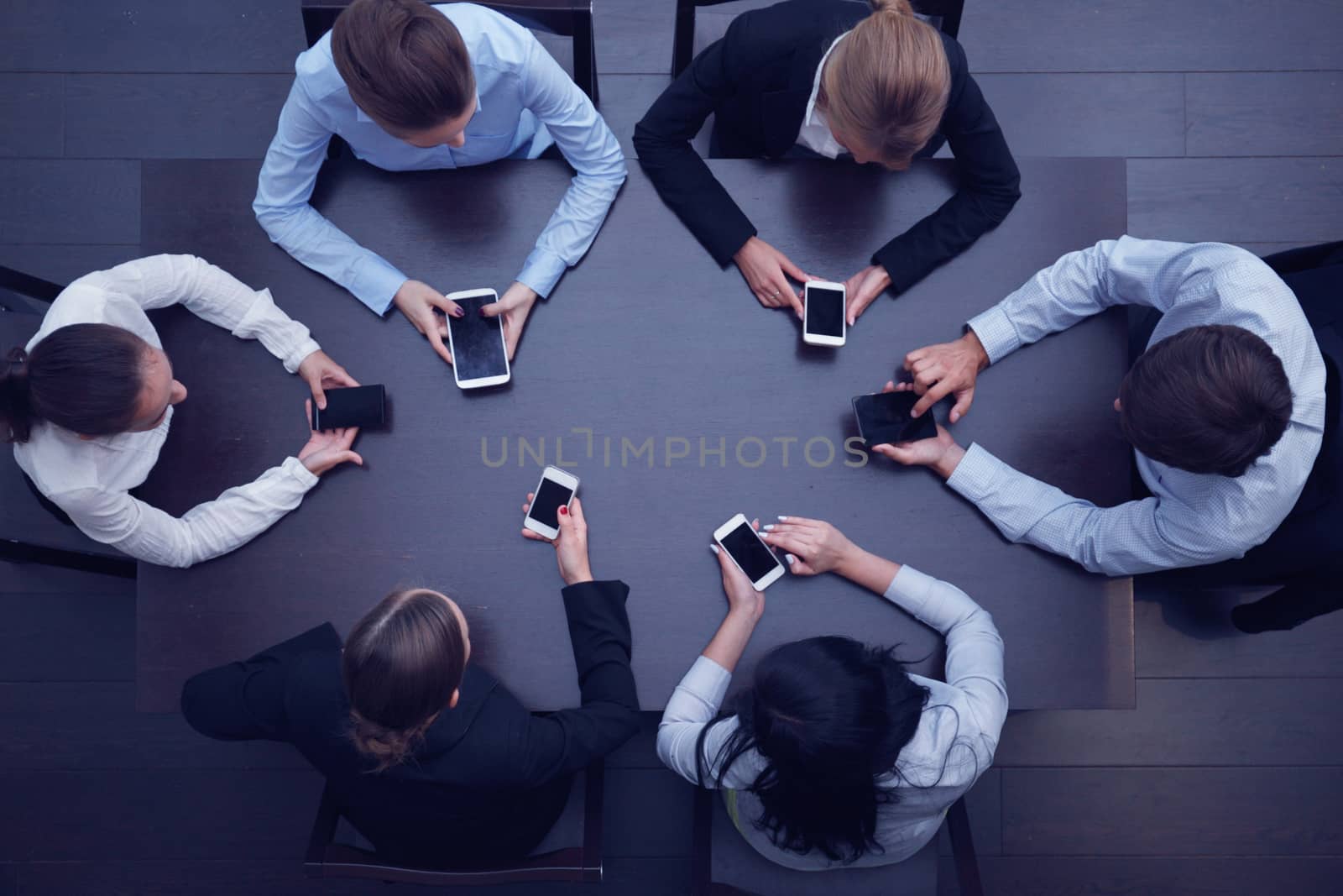 Business people with smartphones sitting around the table, top view