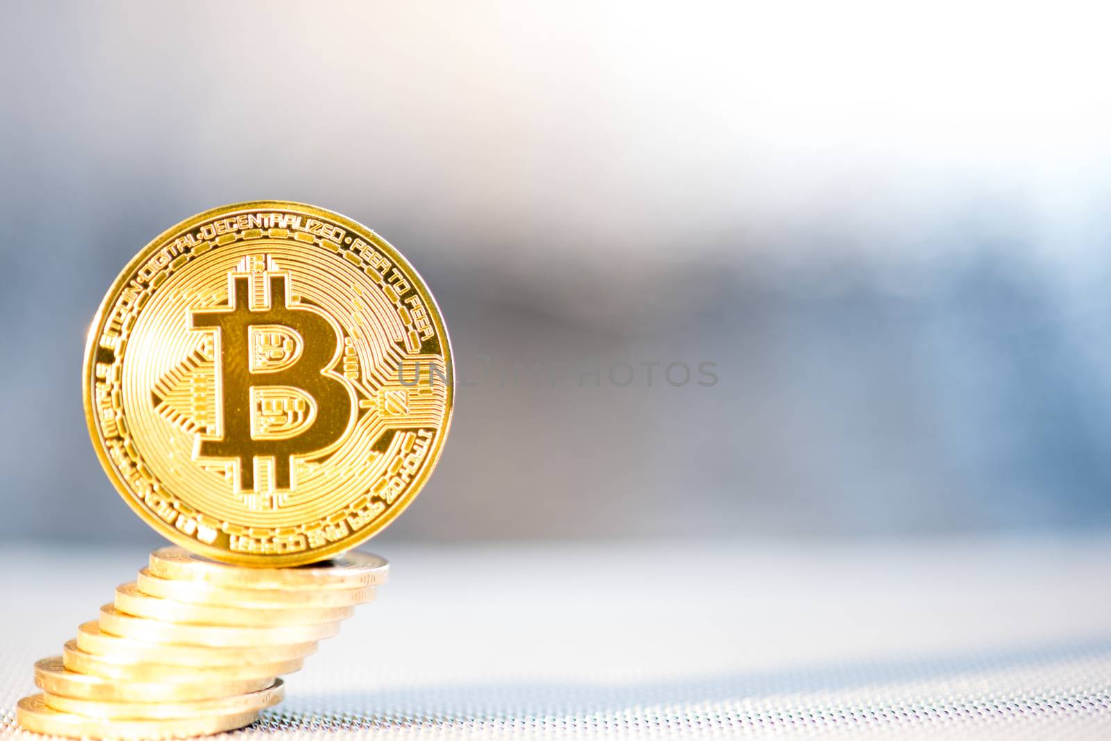 Front view of single golden bit coin with money stack on silver metallic background and surface