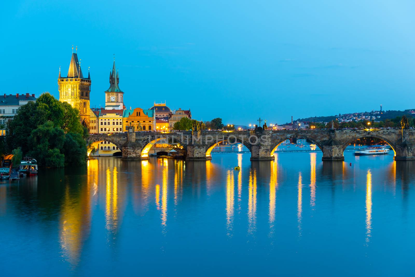 Illuminated Charles Bridge reflected in Vltava River. Evening in Prague, Czech Republic.