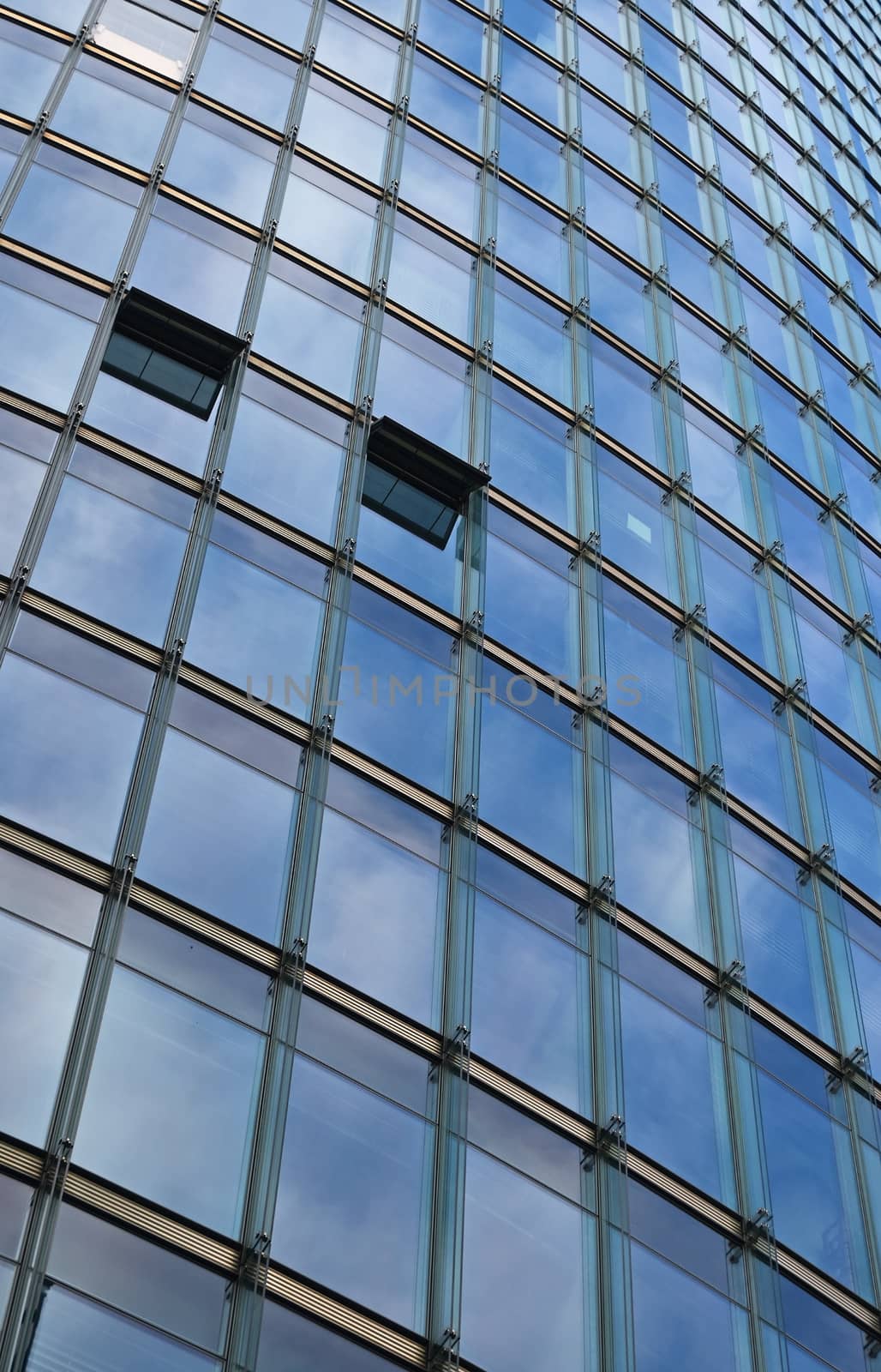 Background texture of modern business skyscraper building glass windows pattern reflecting blue sky, low angle view