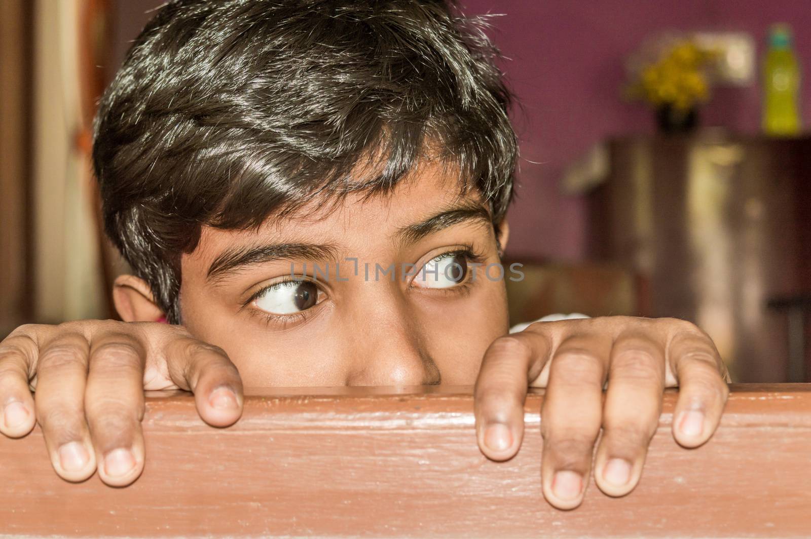 Young boy curiously looking outside through a window. by sudiptabhowmick
