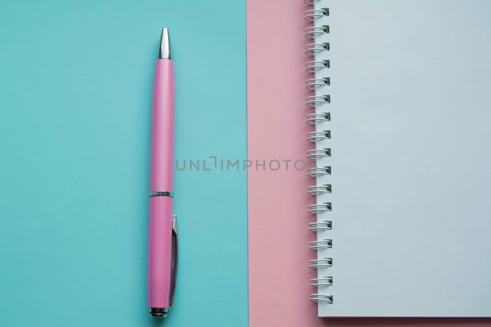 Creative flat lay, top view office Desk. Workspace with blank space for text, Notepad, pen, stationery for female blogger, freelancer on pink and blue background
