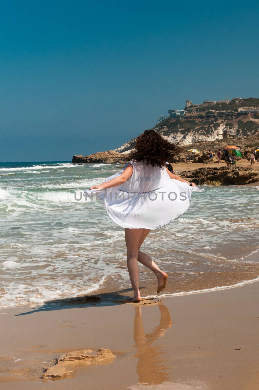 The girl in a white dress whirls in dance on the beach by ben44