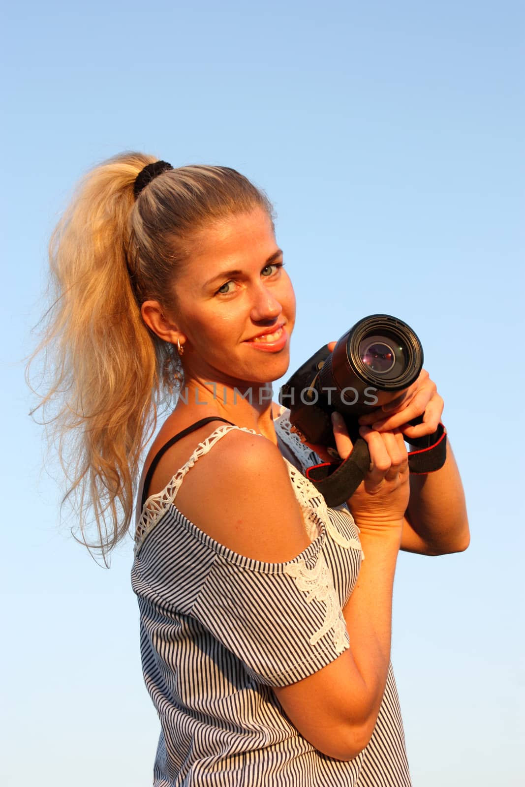 Blonde girl with camera. Smiling and looking in the camera.