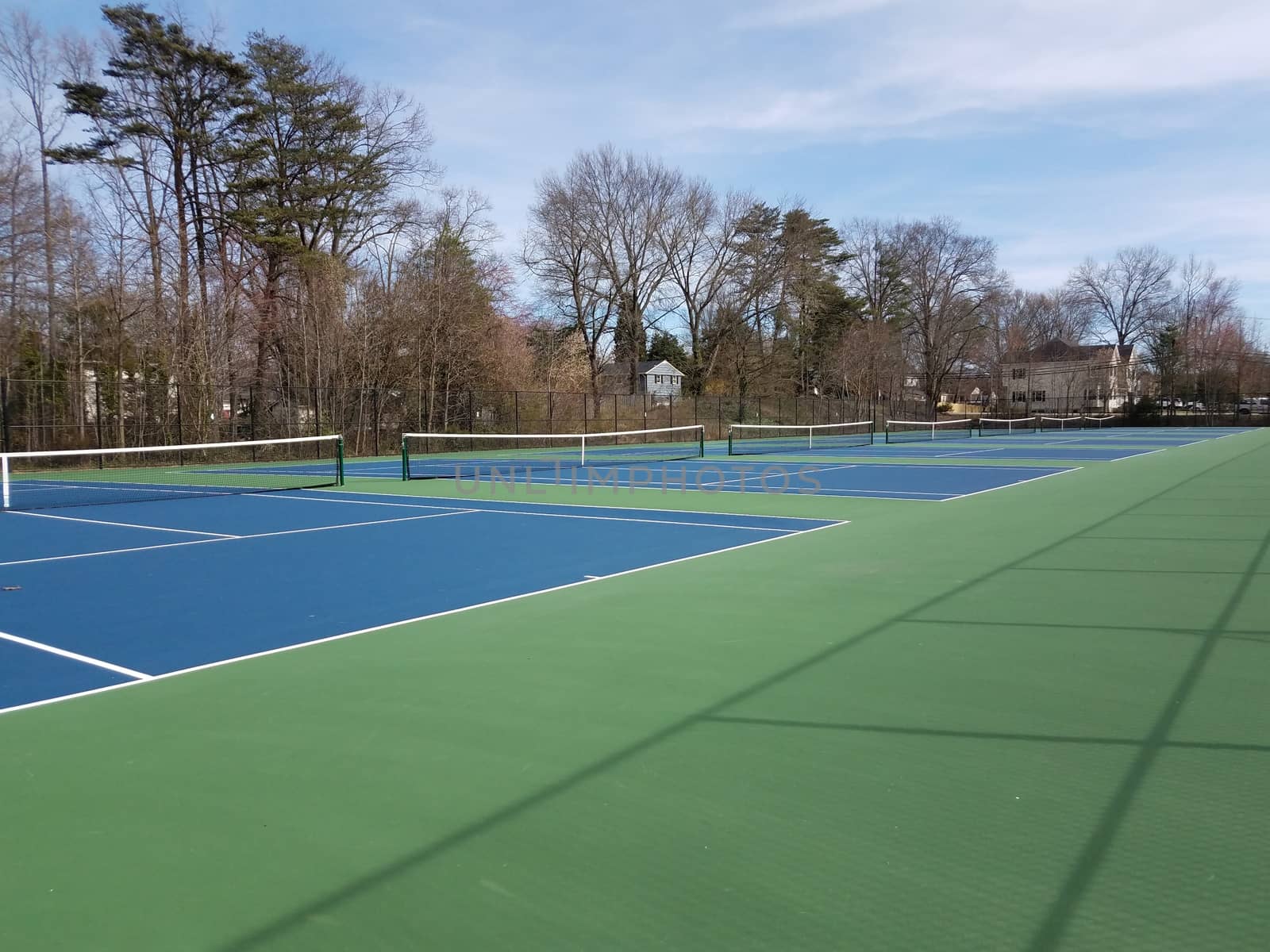 green and blue surface tennis courts with net by stockphotofan1