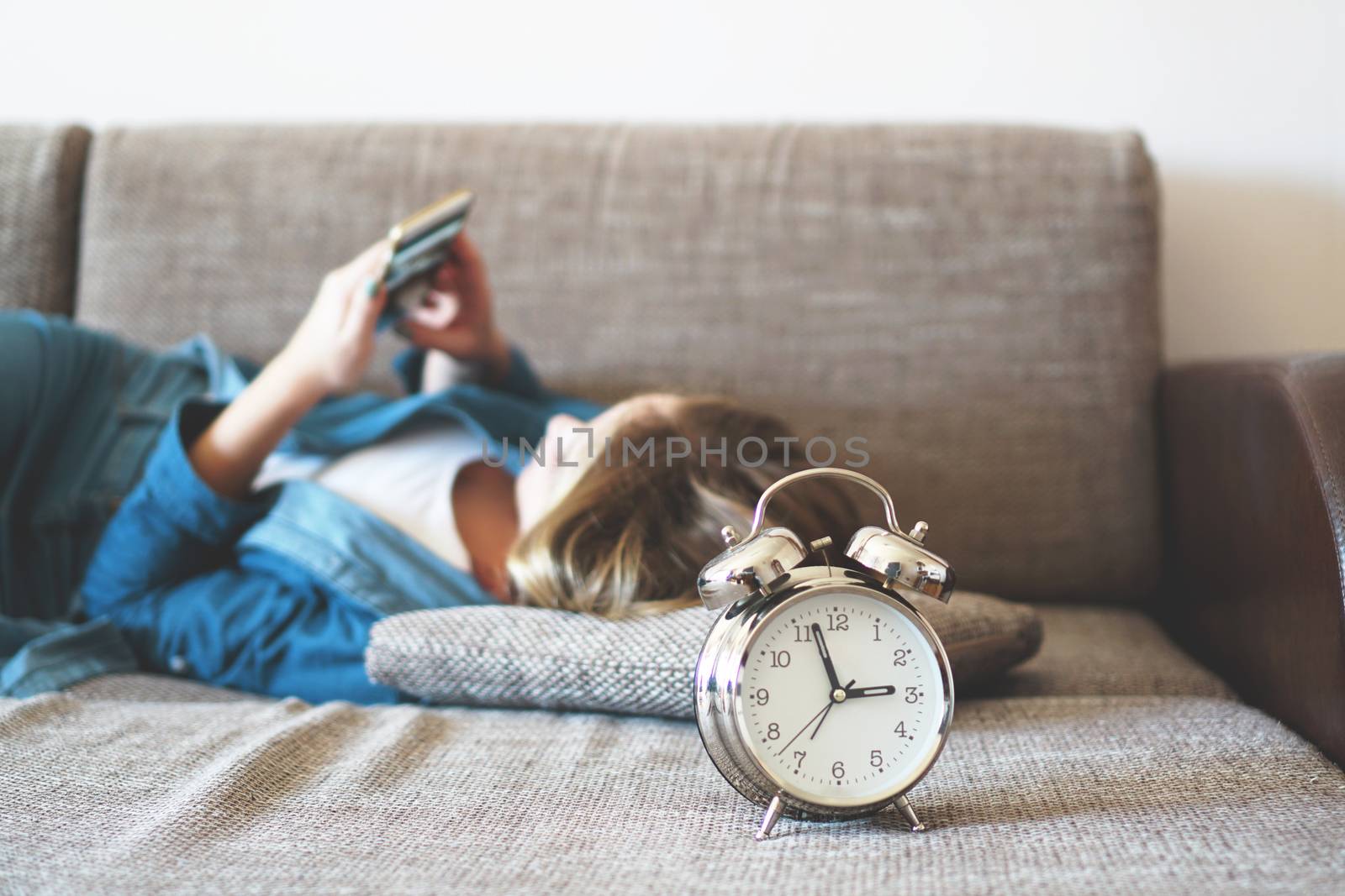 Young woman using phone in bed, looking at screen, insomnia, check time by natali_brill