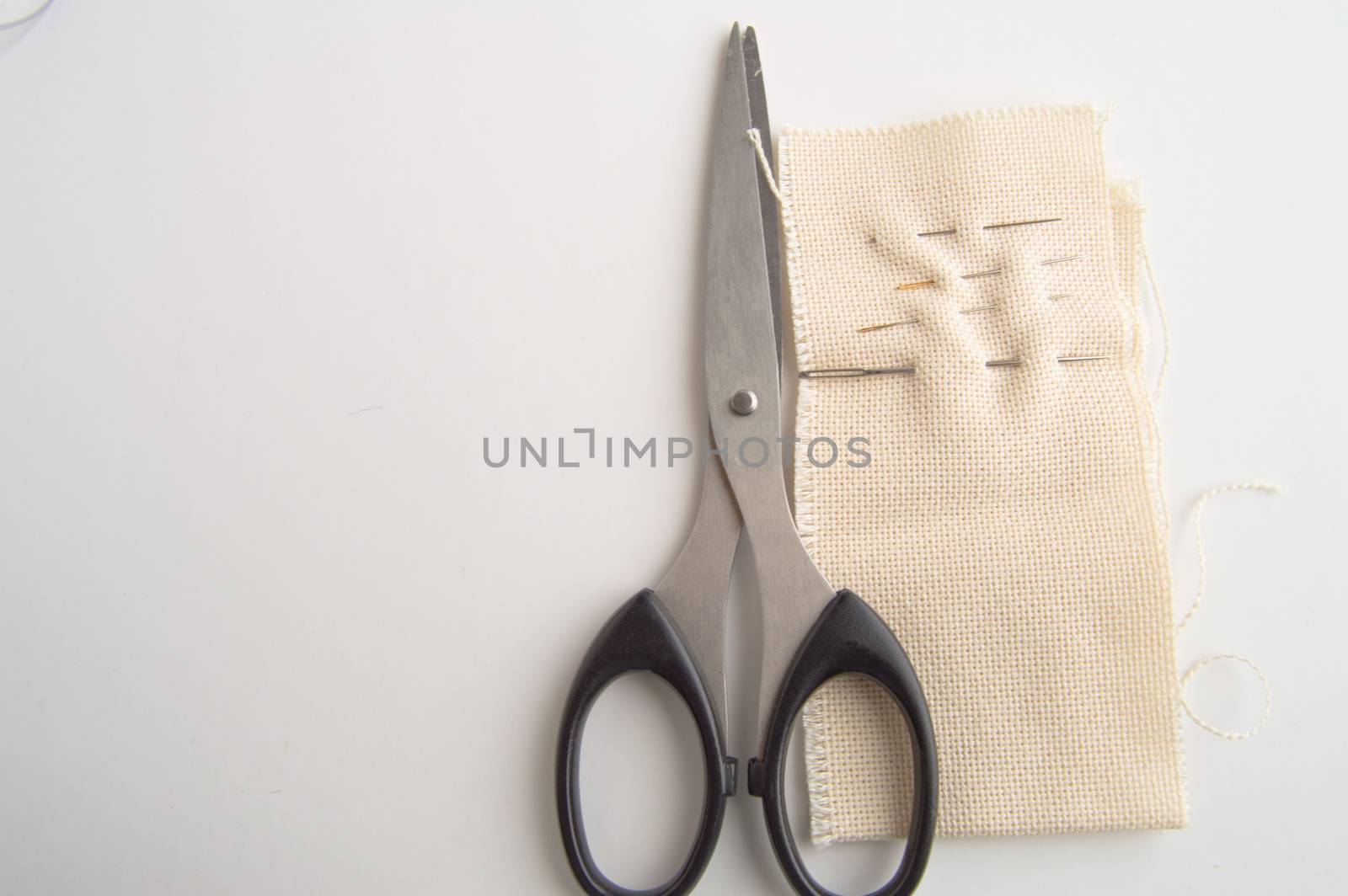 Sewing supplies SCISSORS, NEEDLE, fabric on white table, concept of minimalist, top, and accessories for handmade tailor.