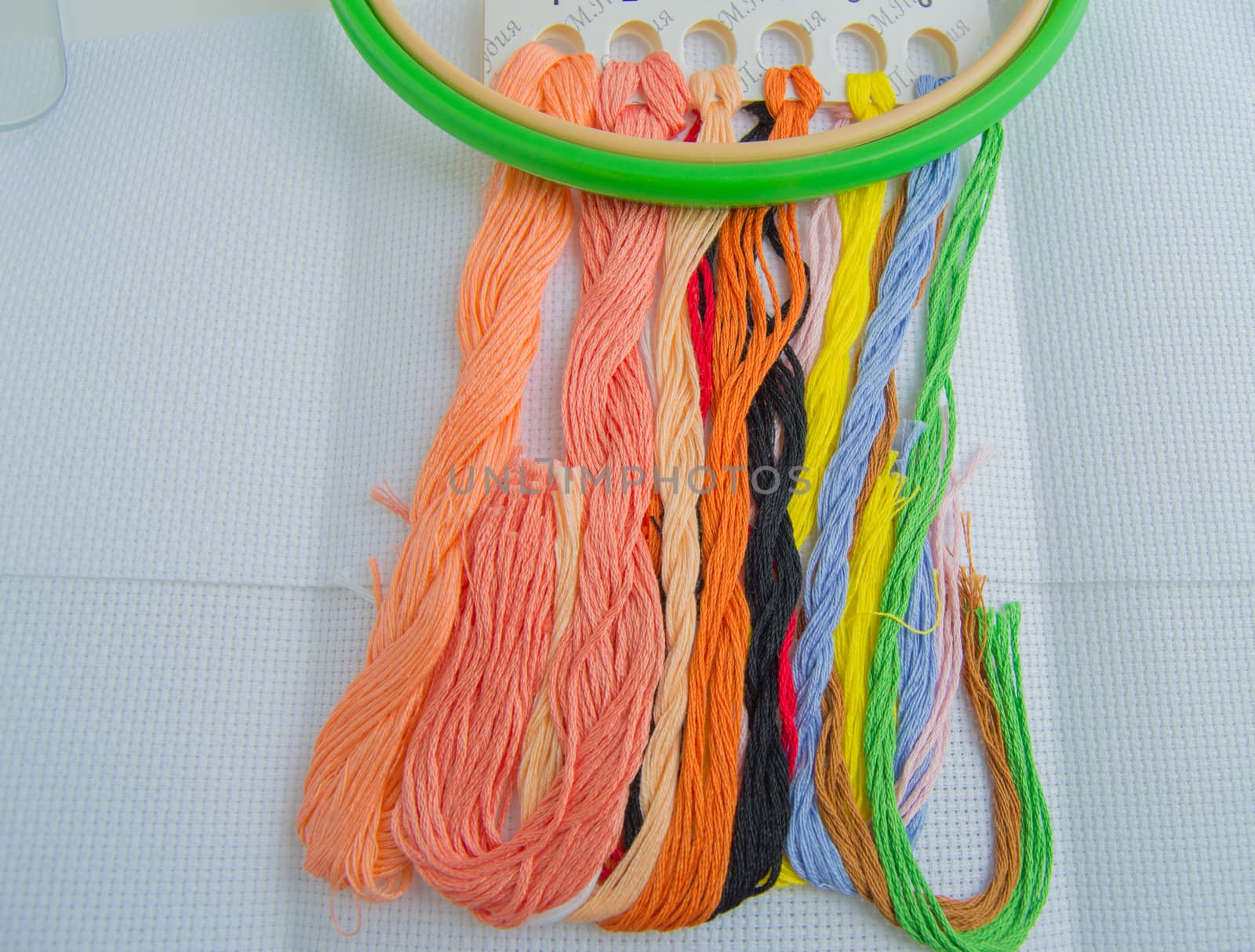 Bright colorful thread for embroidery thread on canvas. Handmade accessories on white background. Place for text, top view.